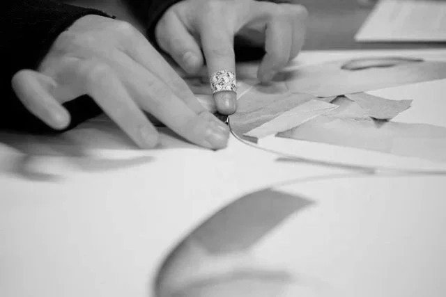 Black & white photo of a girls hands sticking down images and tape onto her own piece of protest art.