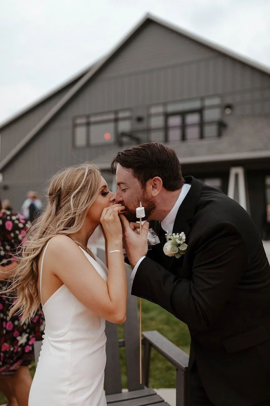 Bride and Groom eating S'mores outside of Lake House Venue