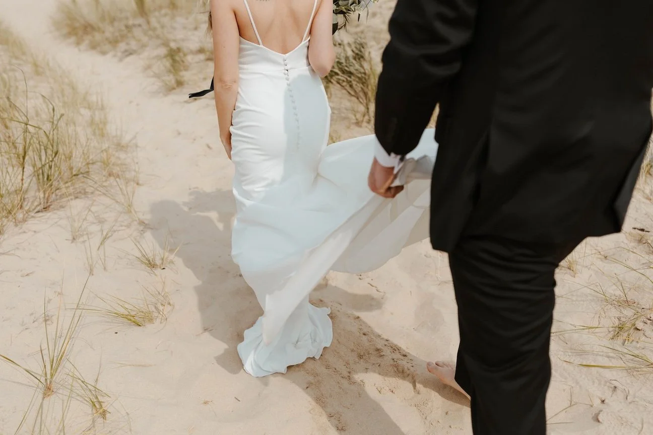 Groom Carrying Brides Train, couple walking in sand