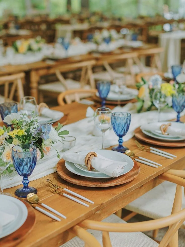 beautiful natural table with blue goblets and colorful floral centerpieces