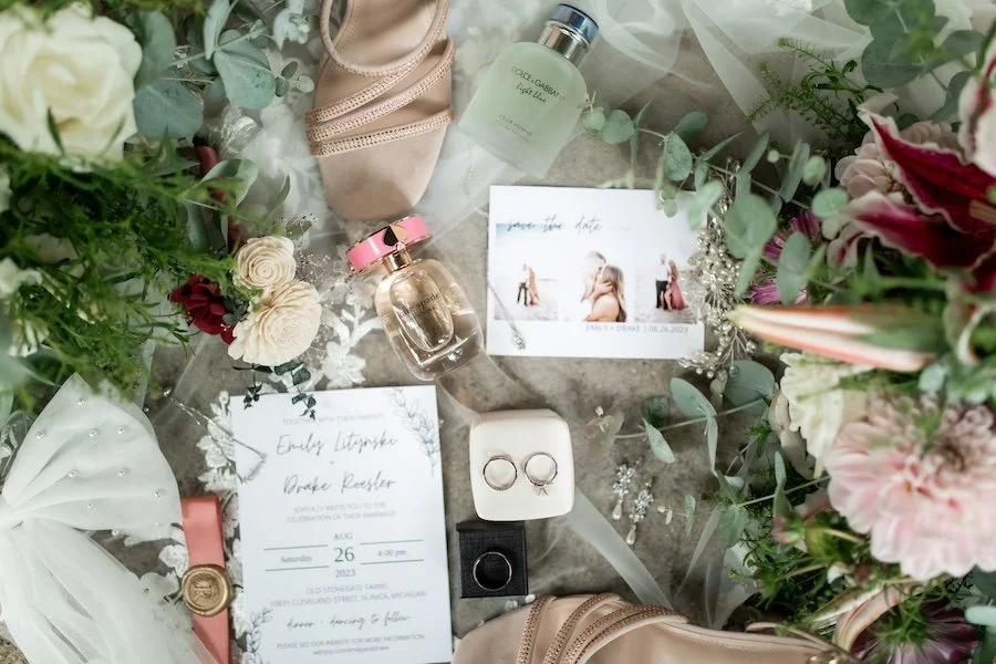 beautiful floral wedding invitation and details photo to include engagement rings and ceremony bands, lace, bows and veil