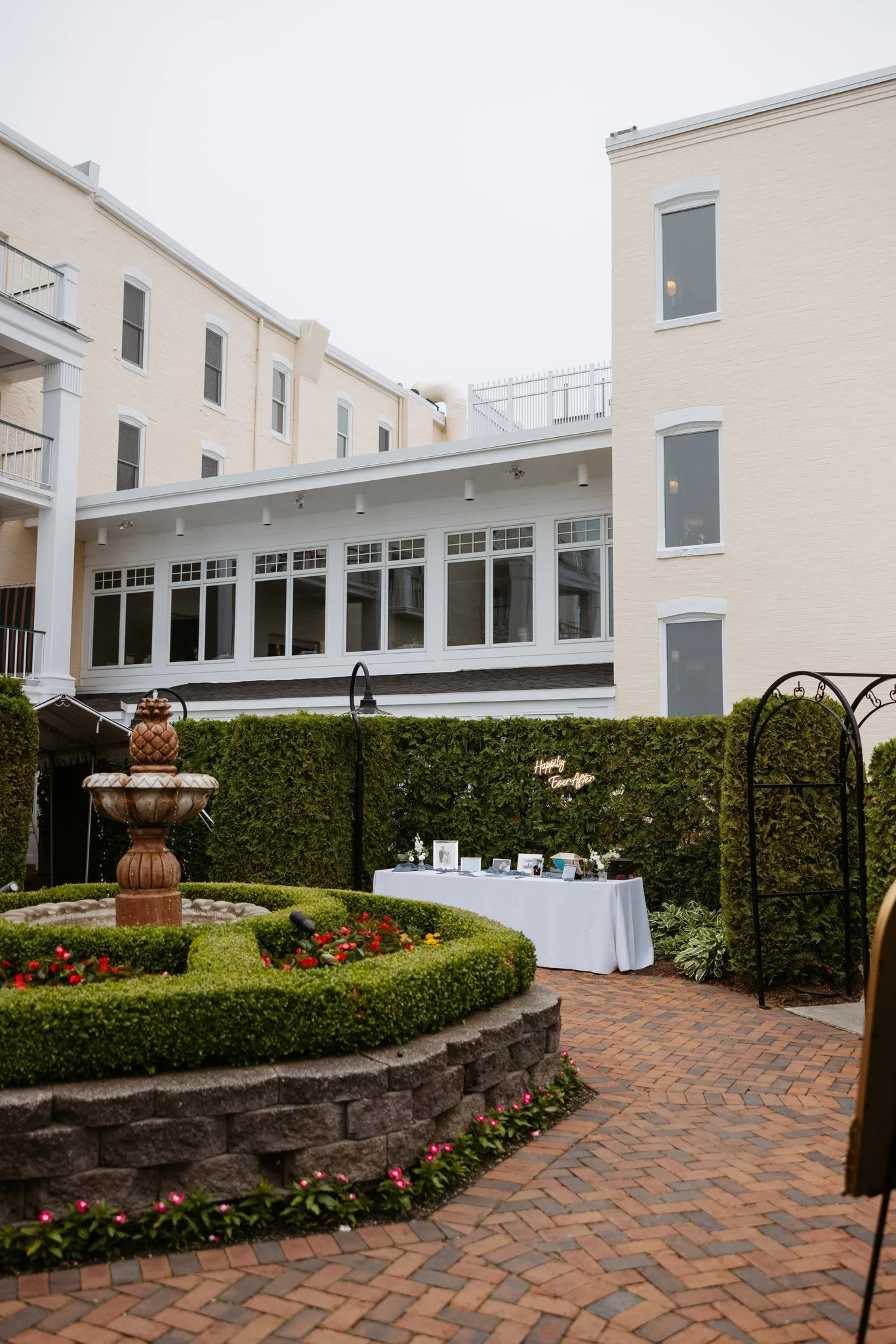 Perry Hotel courtyard with a fountain, garden beds and a wedding welcome table in Petoskey. Photography by Amelie Ferdais.
