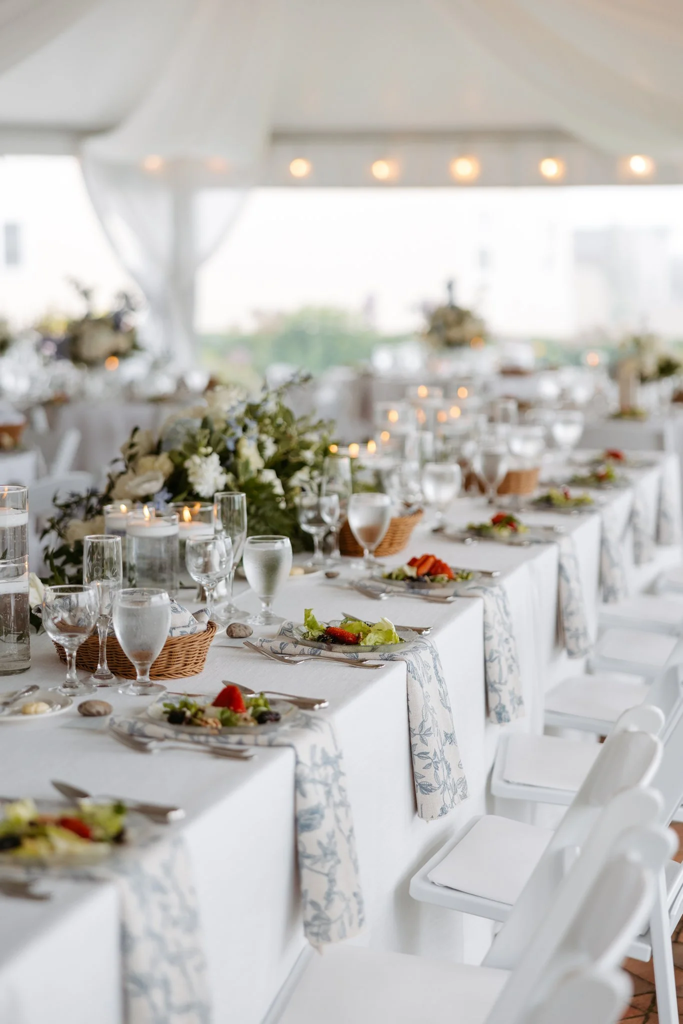 Wedding reception tables at the Perry Hotel with white linens, patterned napkins, flowers and Petoskey stones. Photography by Amelie Ferdais.