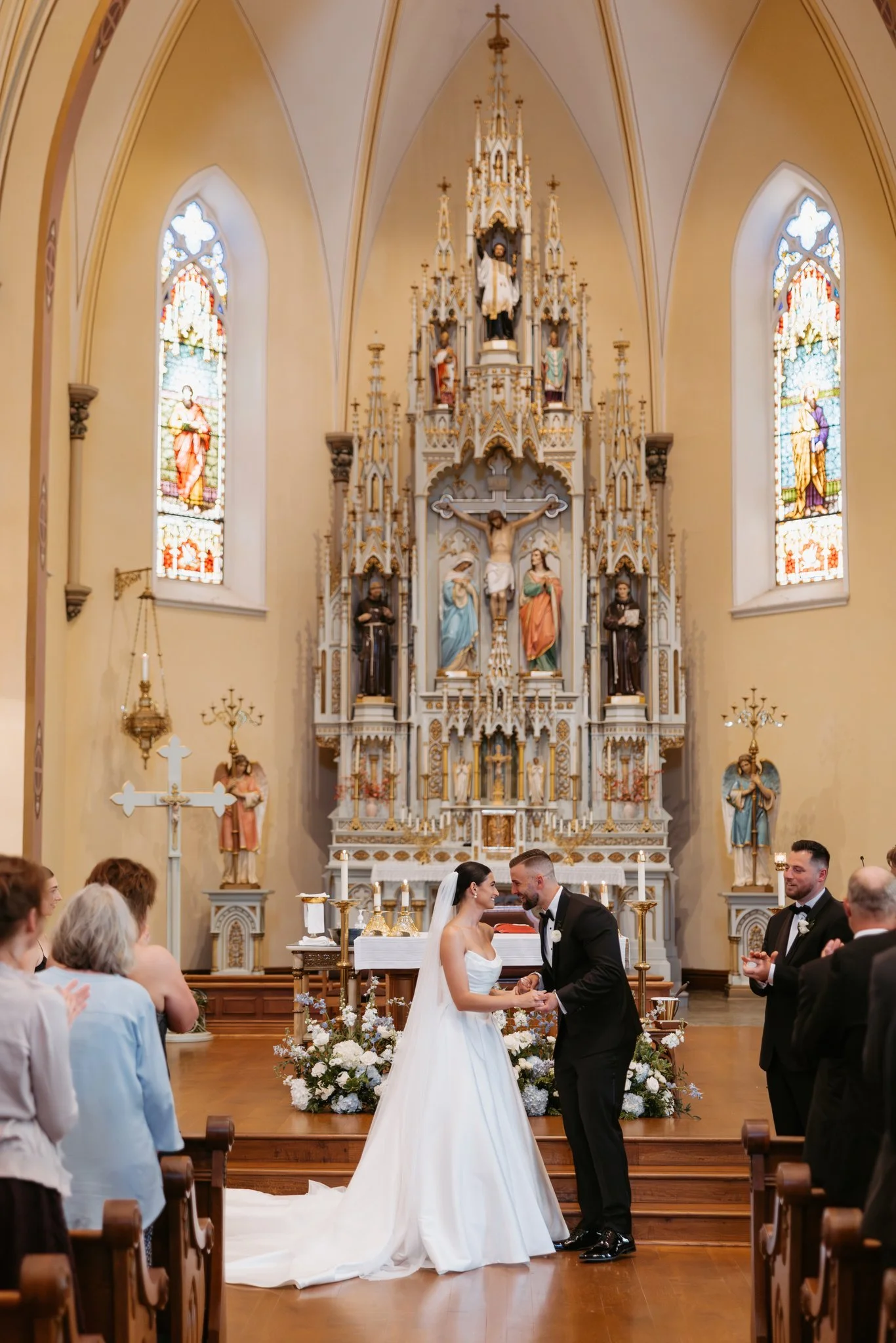 Hannah and Atticus at the altar of St. Francis Xavier Catholic Church during their Petoskey wedding ceremony. Photography by Amelie Ferdais.