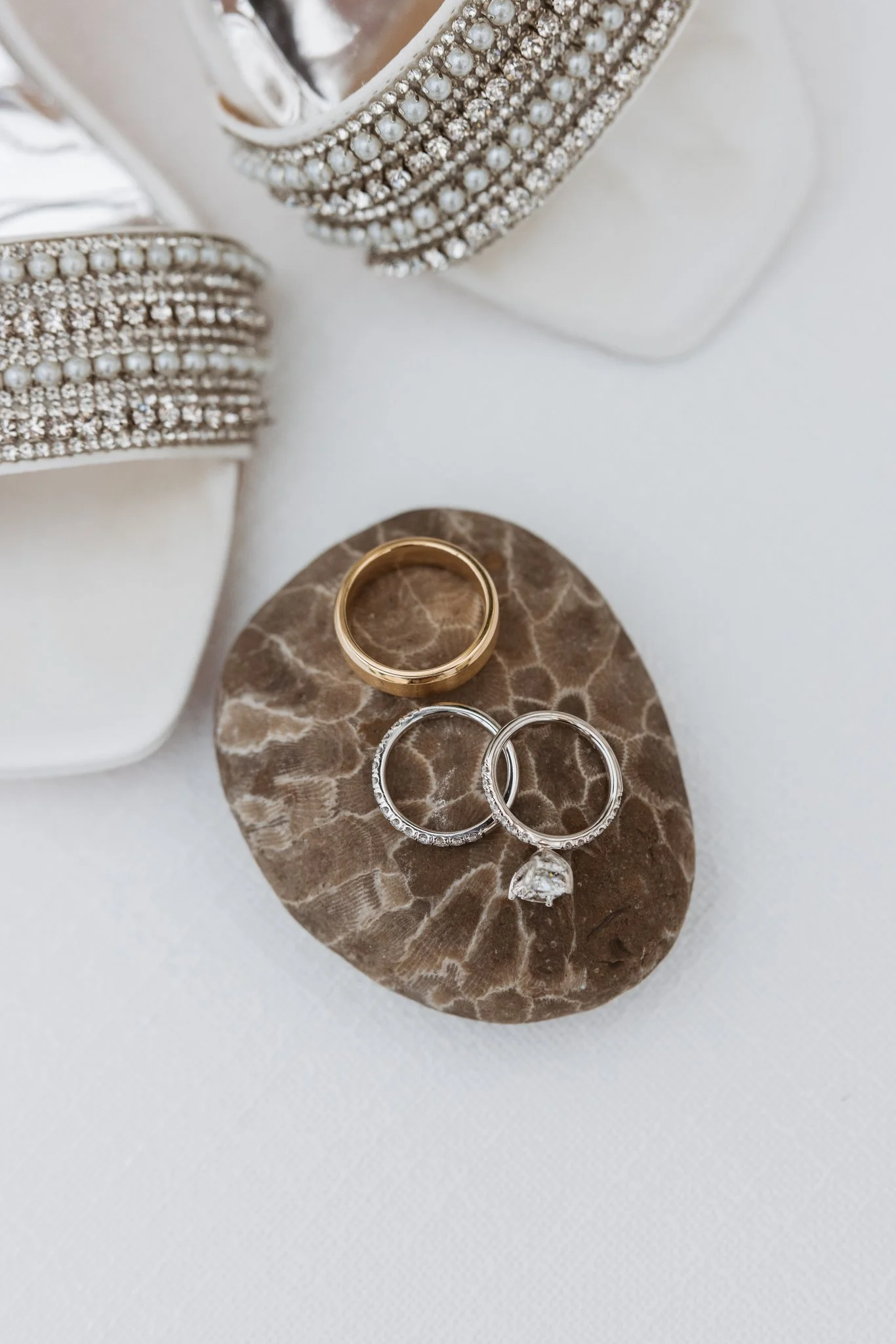 Wedding rings on a Petoskey stone beside Hannah’s bridal shoes. Photography by Amelie Ferdais.