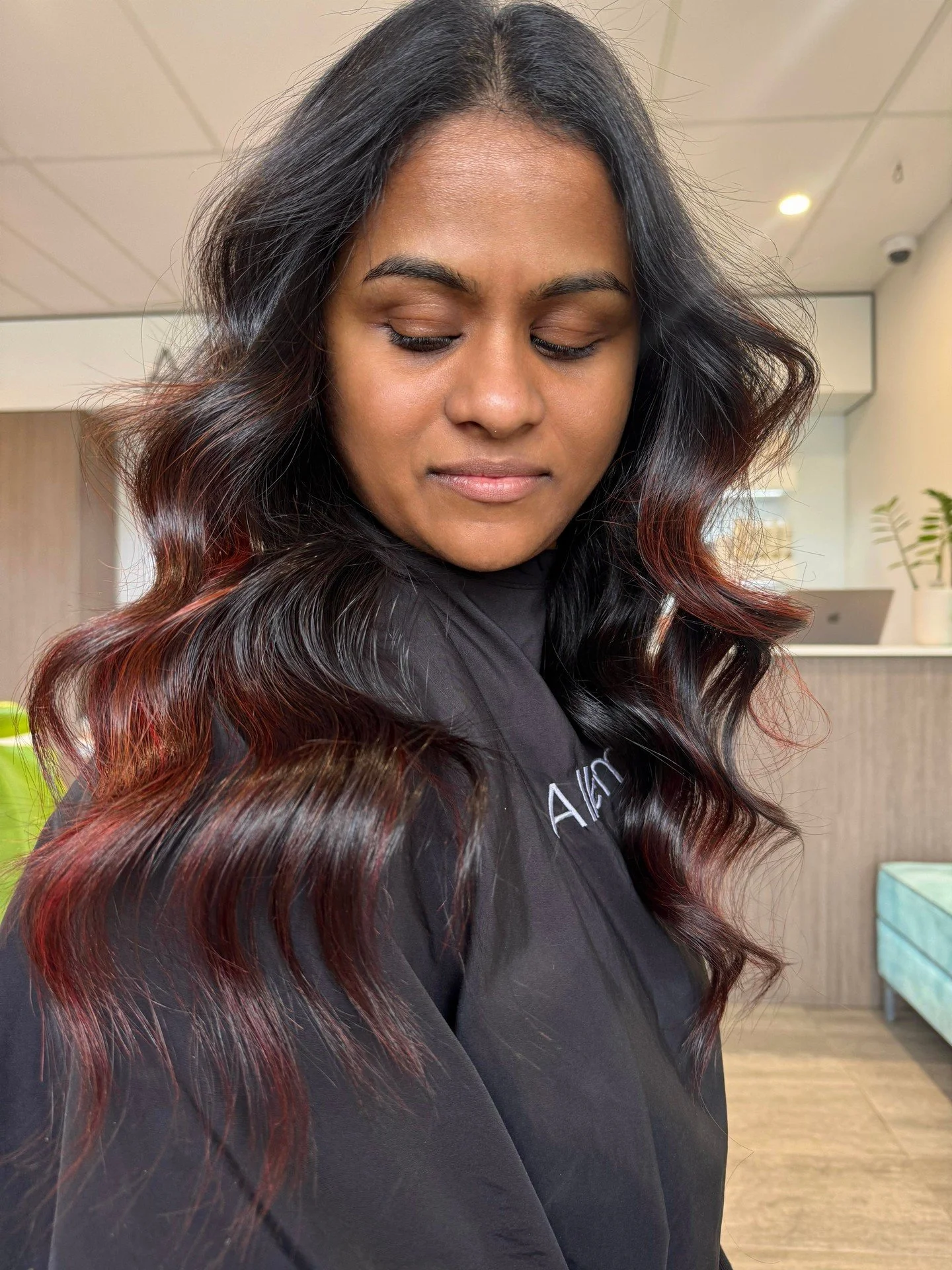 Glossy brunette hair with soft waves, shared by Alkemi Salon.