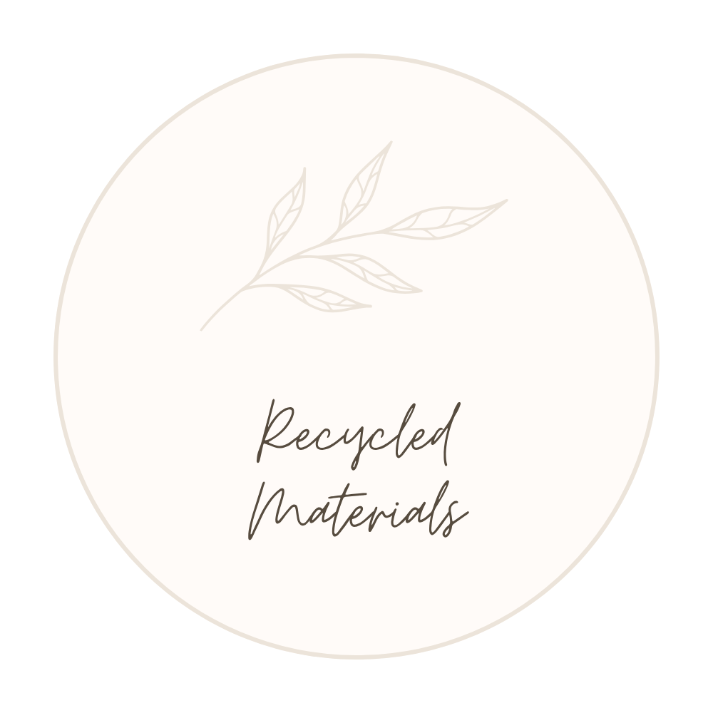 A circular label with a subtle leaf illustration at the top, the words "Recycled Materials" written in elegant script font in the center, on a light beige background.
