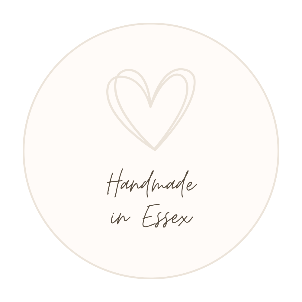 A round white label with a faint heart outline drawn above the words 'Handmade in Essex' written in cursive font.