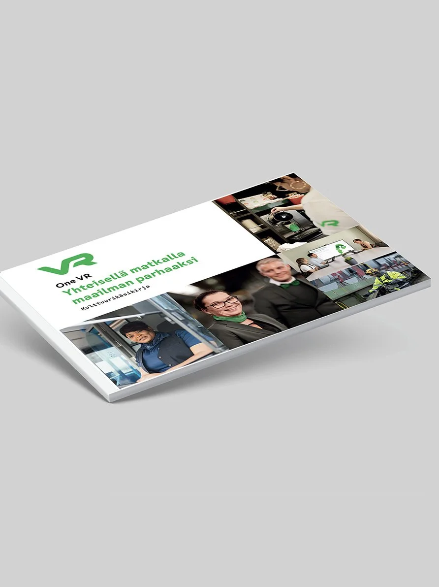 Angled cover of a Finnish One VR corporate magazine featuring employee photos and workplace scenes