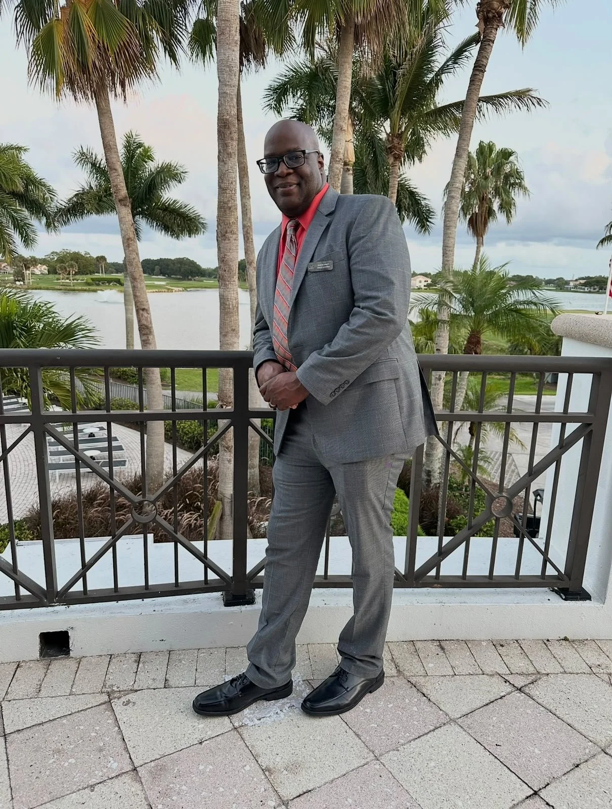 Damon Spady Luxury Travel Advisor standing in a suit amongst palm trees