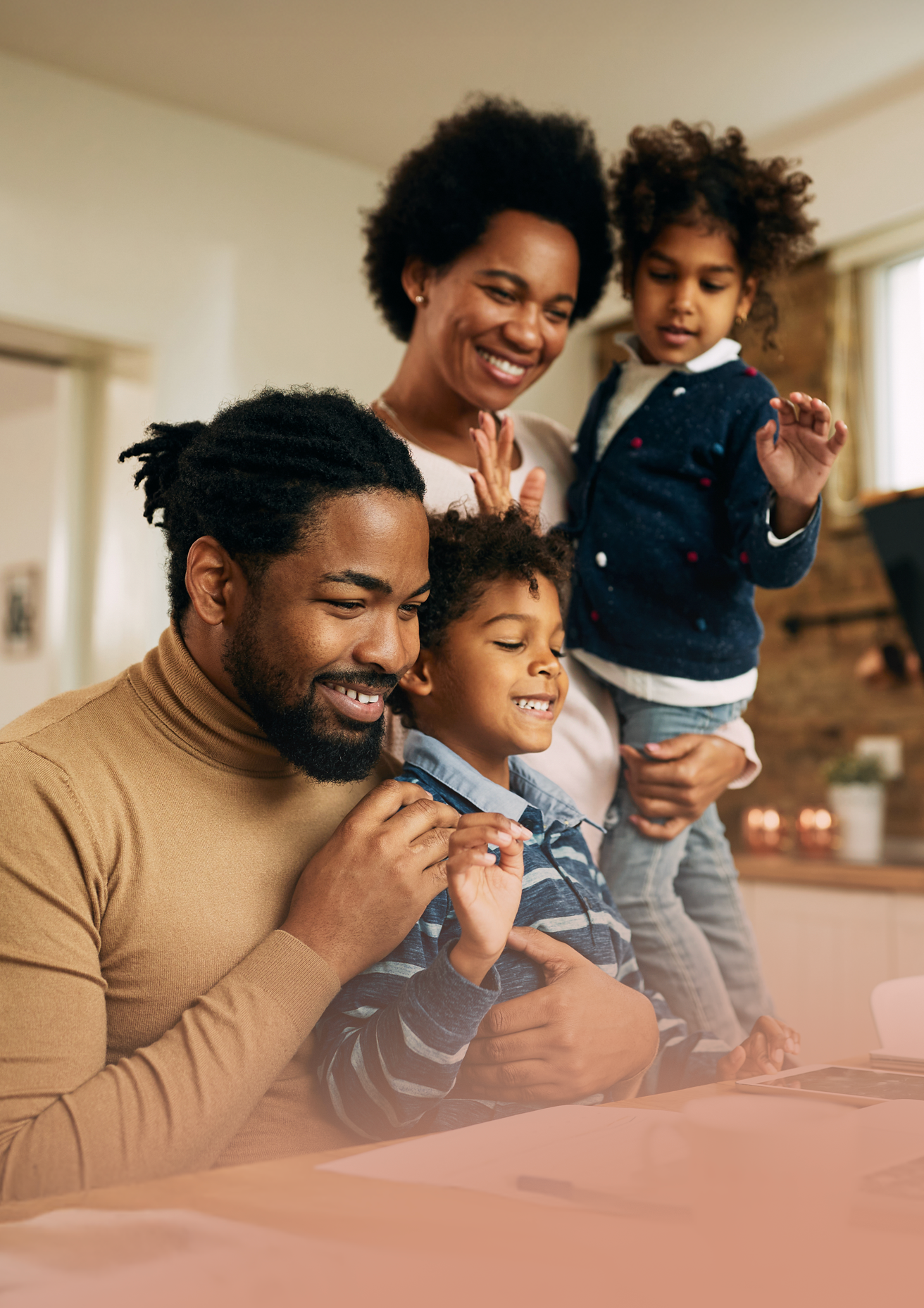 A family of four, including a mother, father, and two children, smiling and enjoying time together indoors.