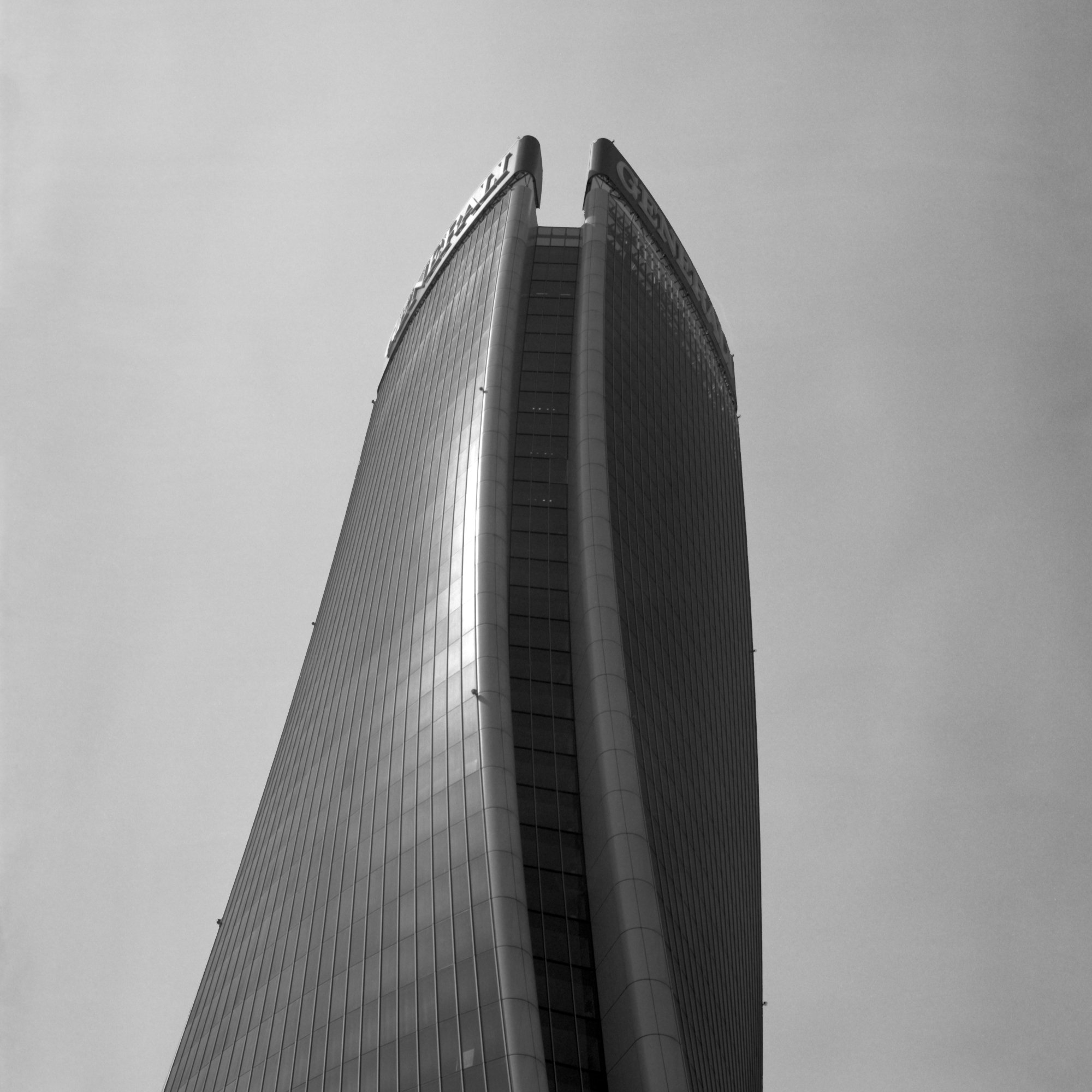 City skyscraper viewed from the ground, with a focus on the building's curved upper section reaching into the sky.