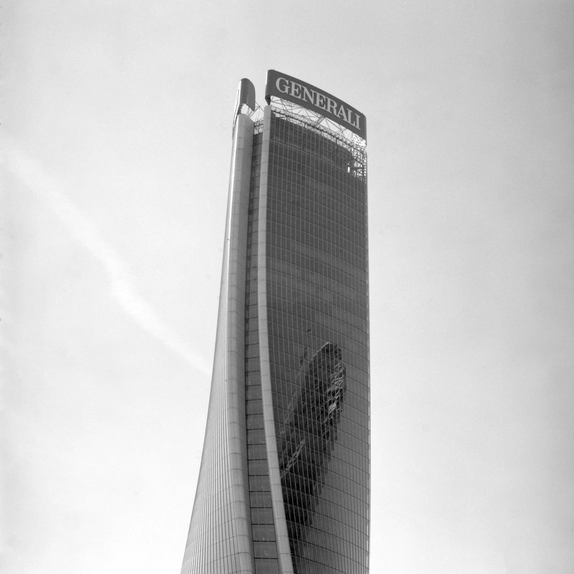 A tall modern skyscraper with a curved facade and a sign at the top that reads 'GENERALI'.