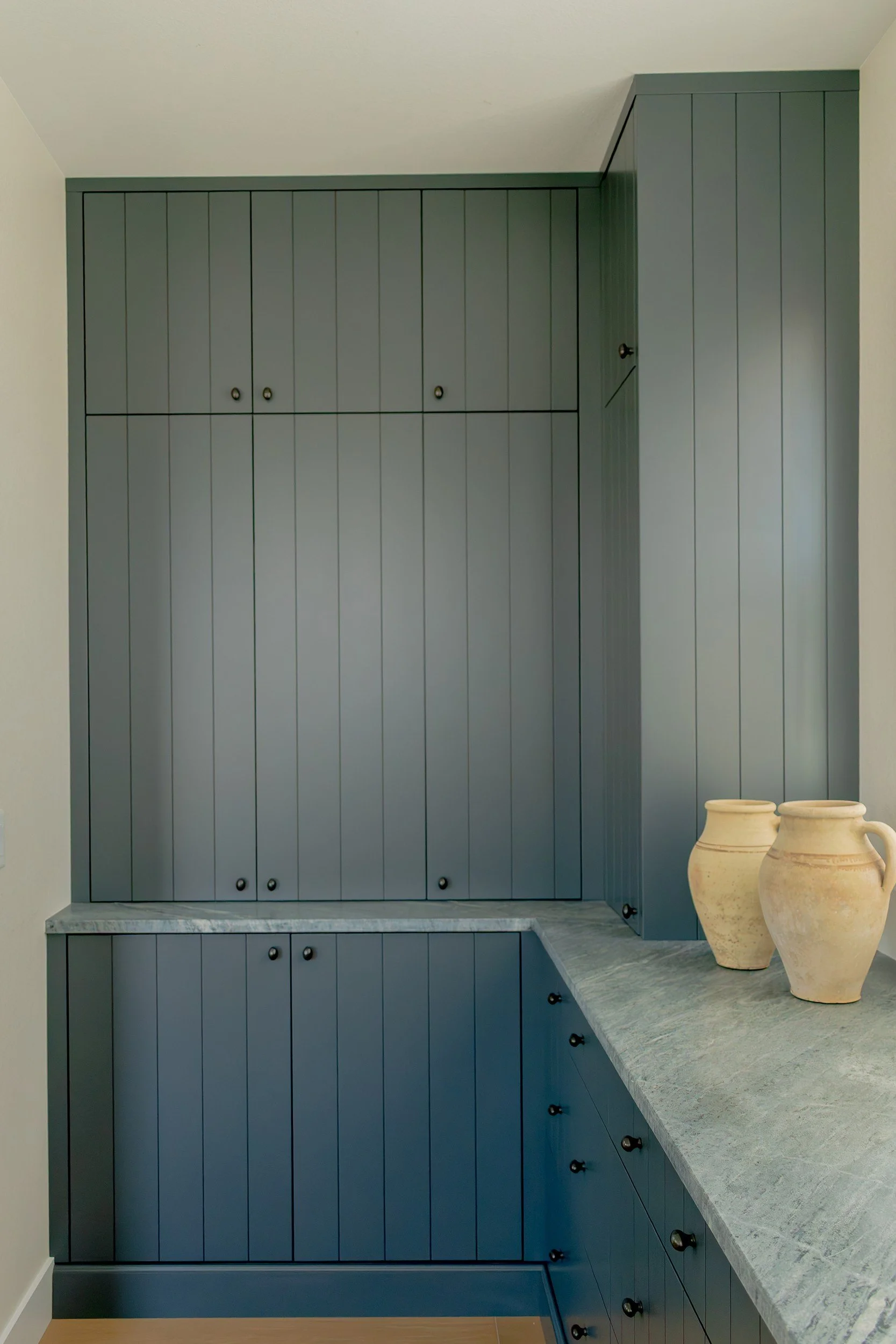 Blue-gray paneled cabinetry with a stone counter