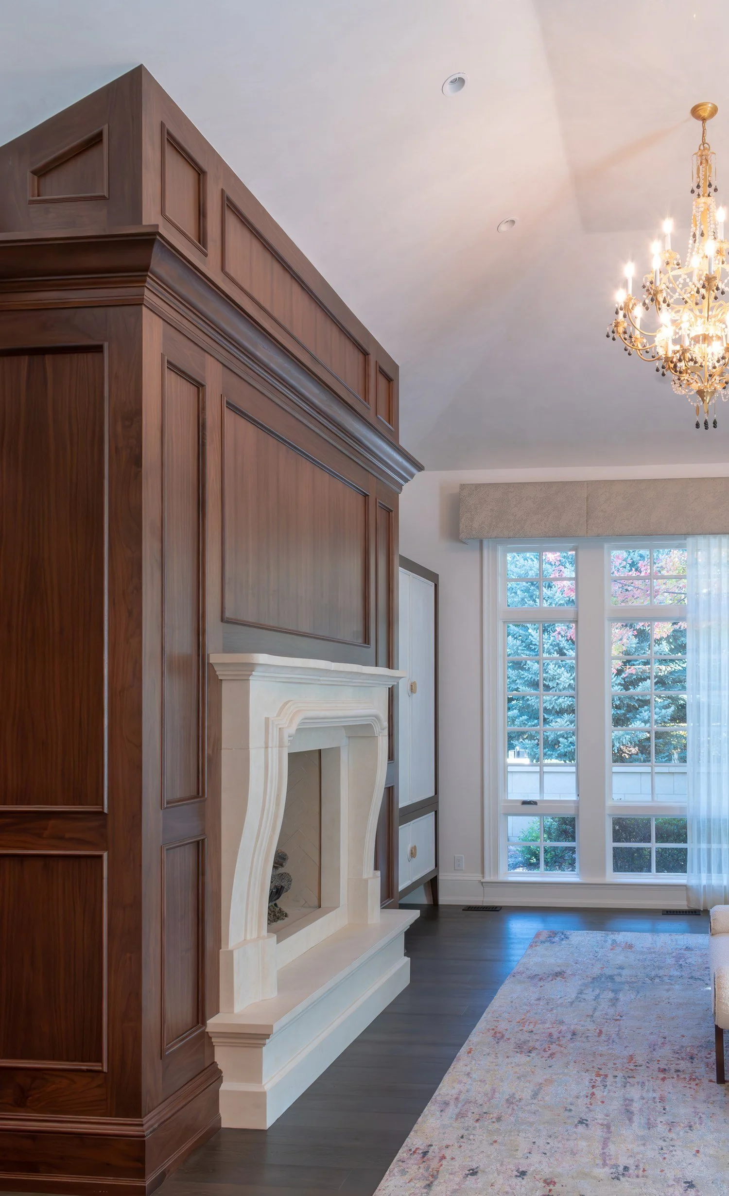 Paneled wood wall with a carved stone fireplace mantel