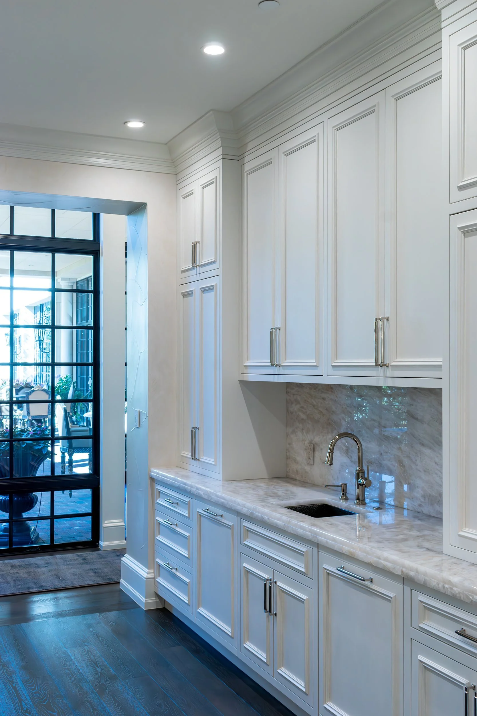 Pantry cabinetry beside a steel-and-glass door