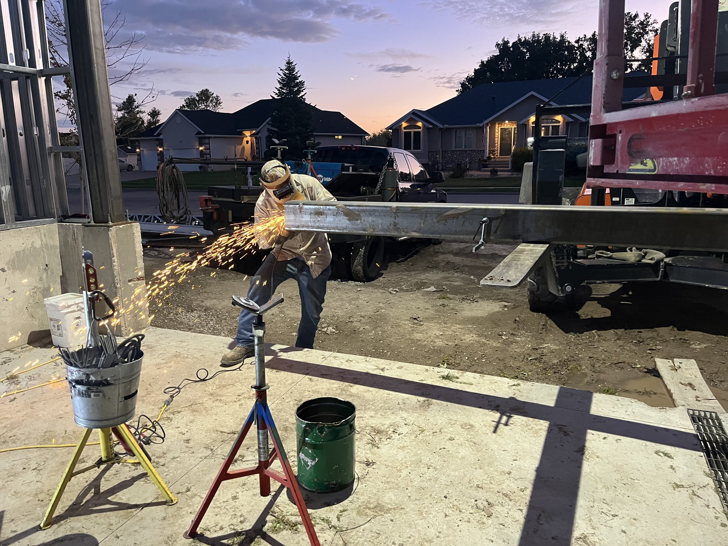 Welder cutting and grinding steel with sparks flying during an on-site fabrication job
