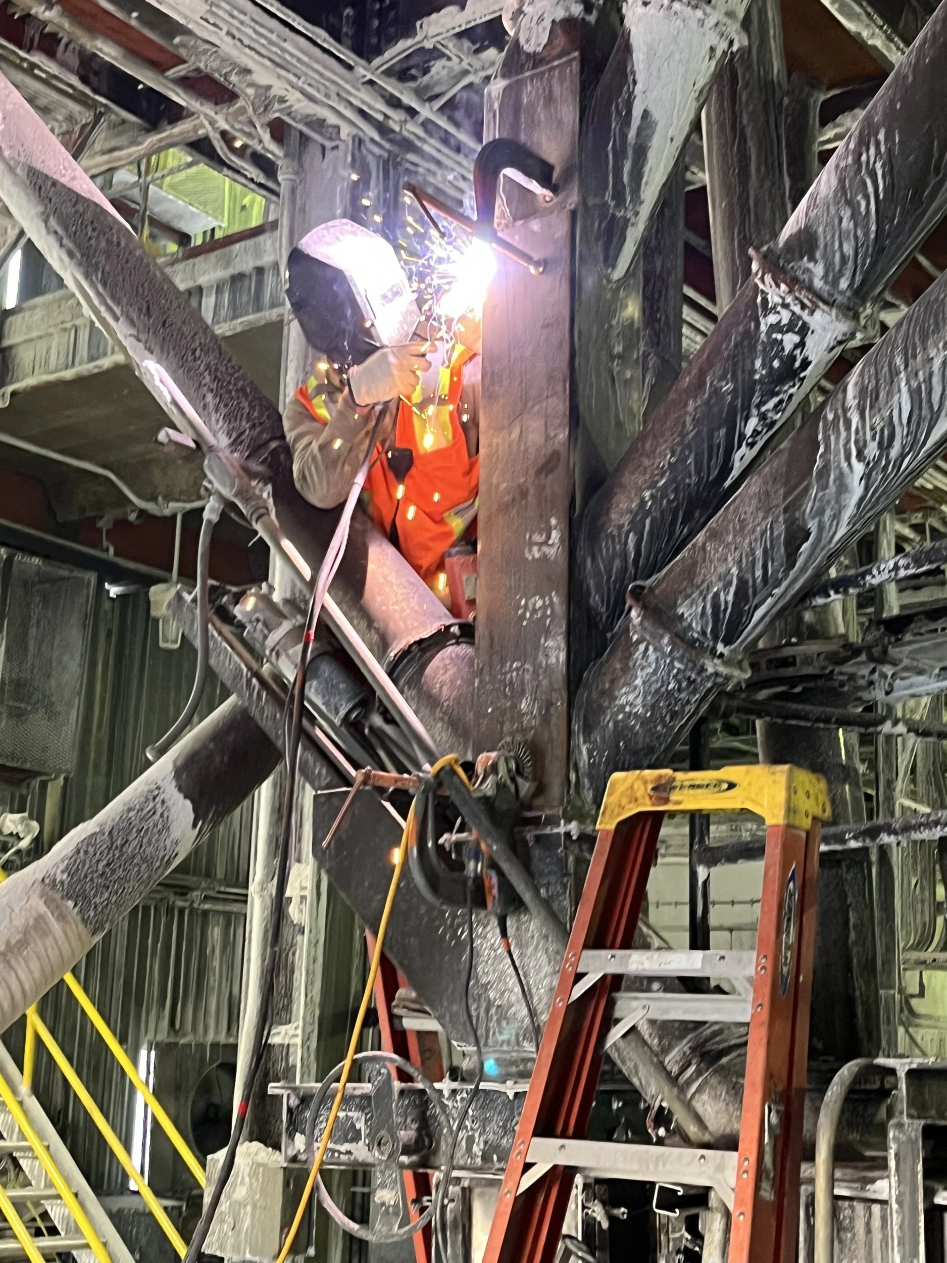 Welder performing overhead structural steel welding on an industrial project
