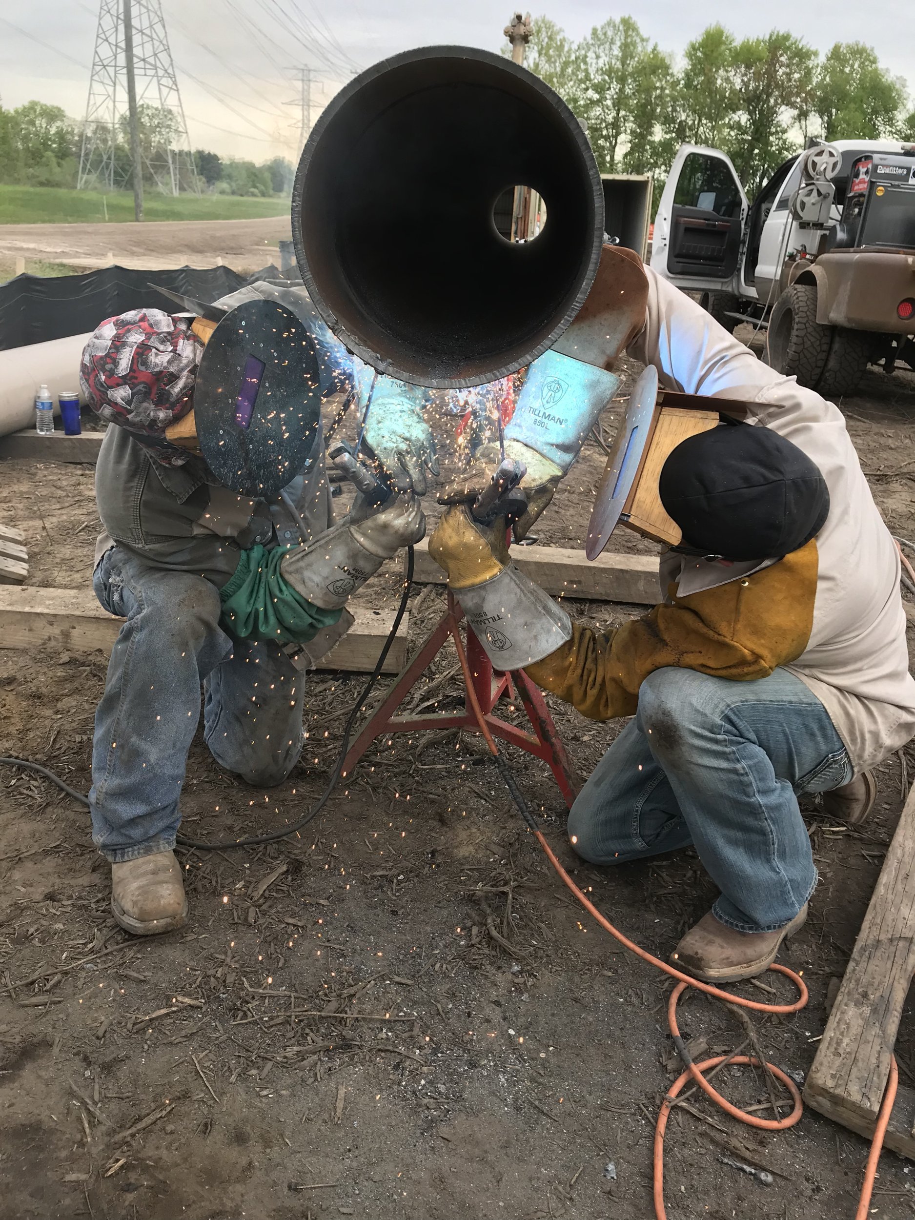 Two welders performing field pipe welding on a large steel pipe at a Utah job site