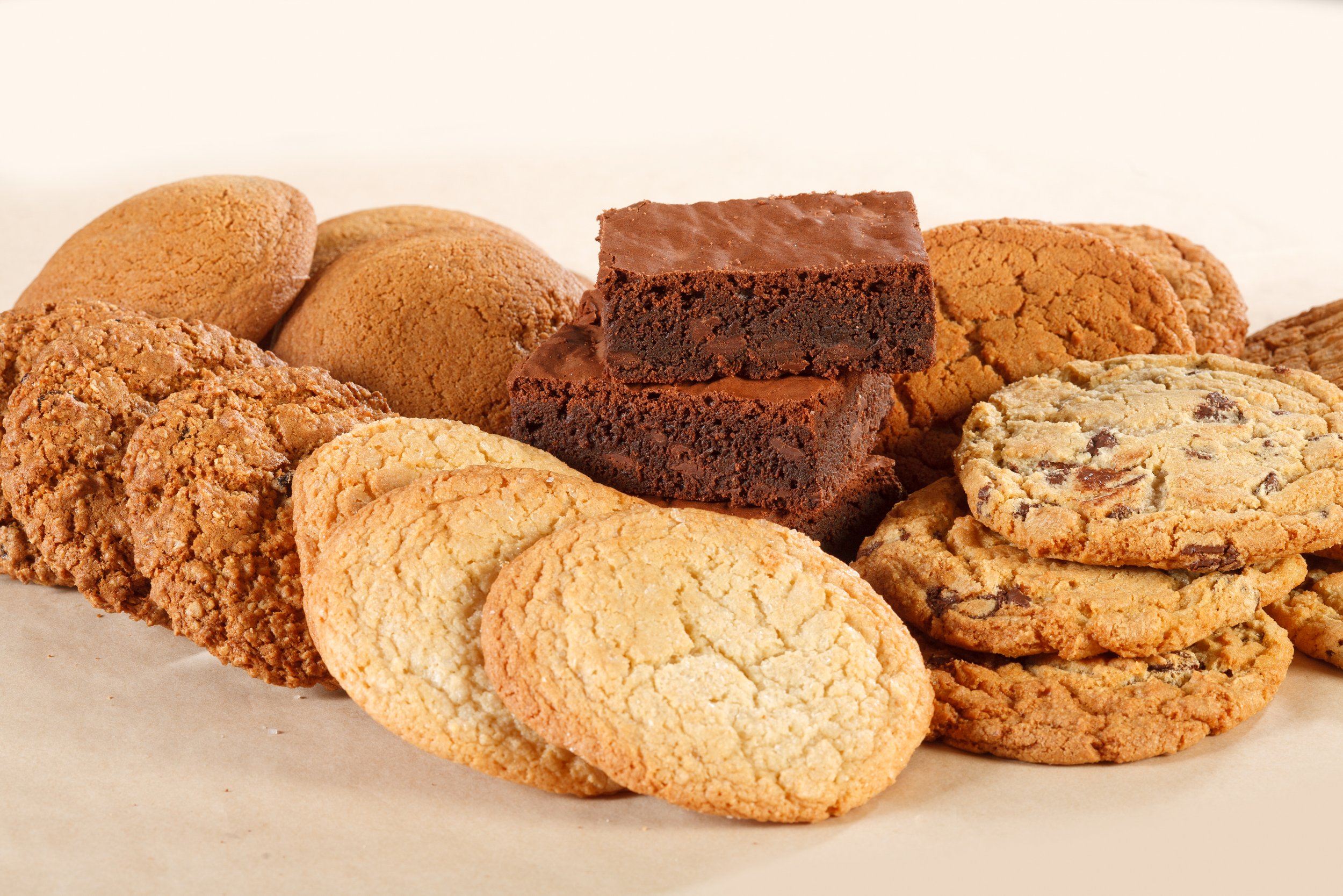 Assorted cookies, including chocolate chip, oatmeal, and peanut butter varieties, arranged on a surface.