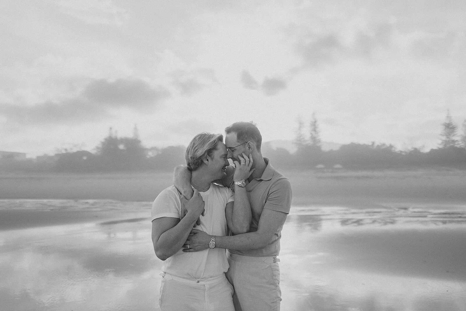 Black and white of the couple with foreheads together on the beach, Byron and Luke's marriage proposal at Cabarita Beach, Northern Rivers