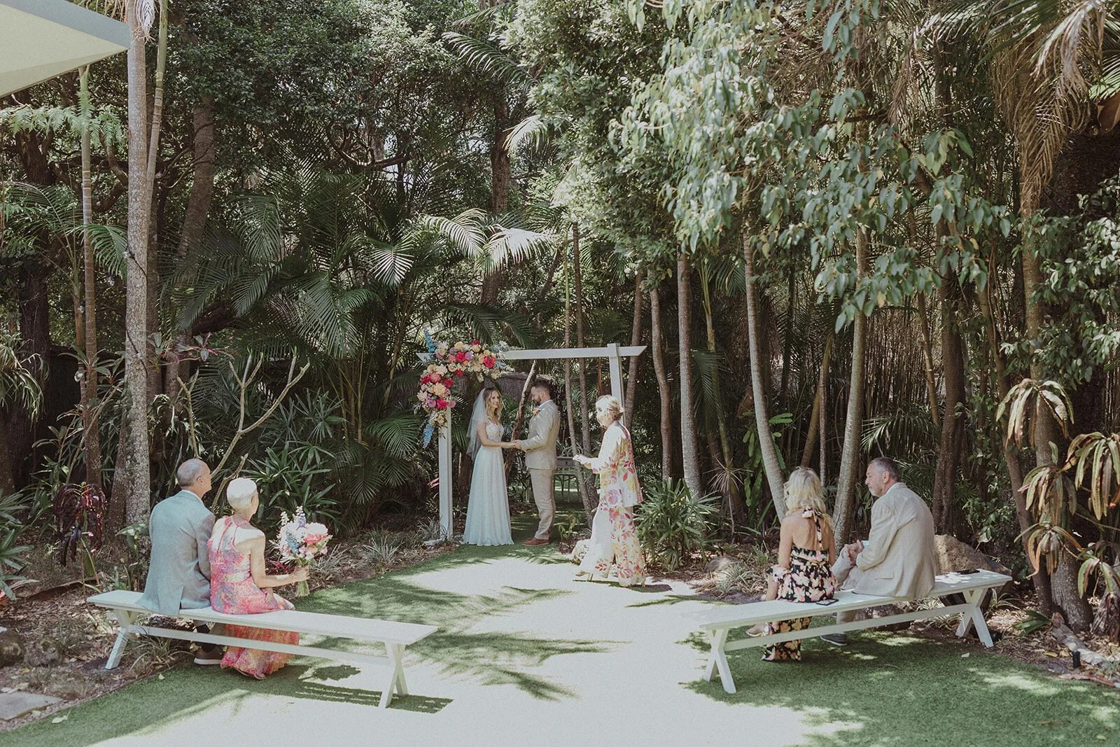 Guests seated on benches at a rainforest garden ceremony, Eliza and Greg's elopement at Broken Head, Byron Bay