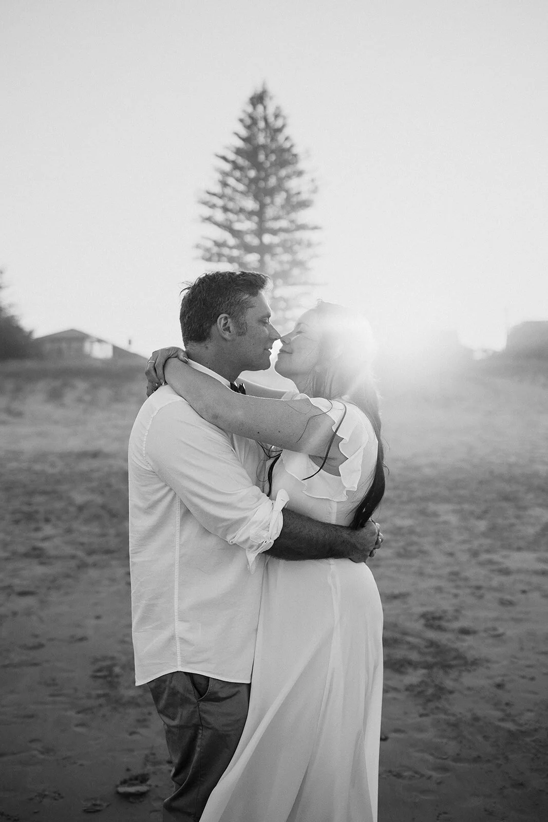 Black and white of the couple embracing in the sunset, Maritess and Mark's elopement at Lennox Head