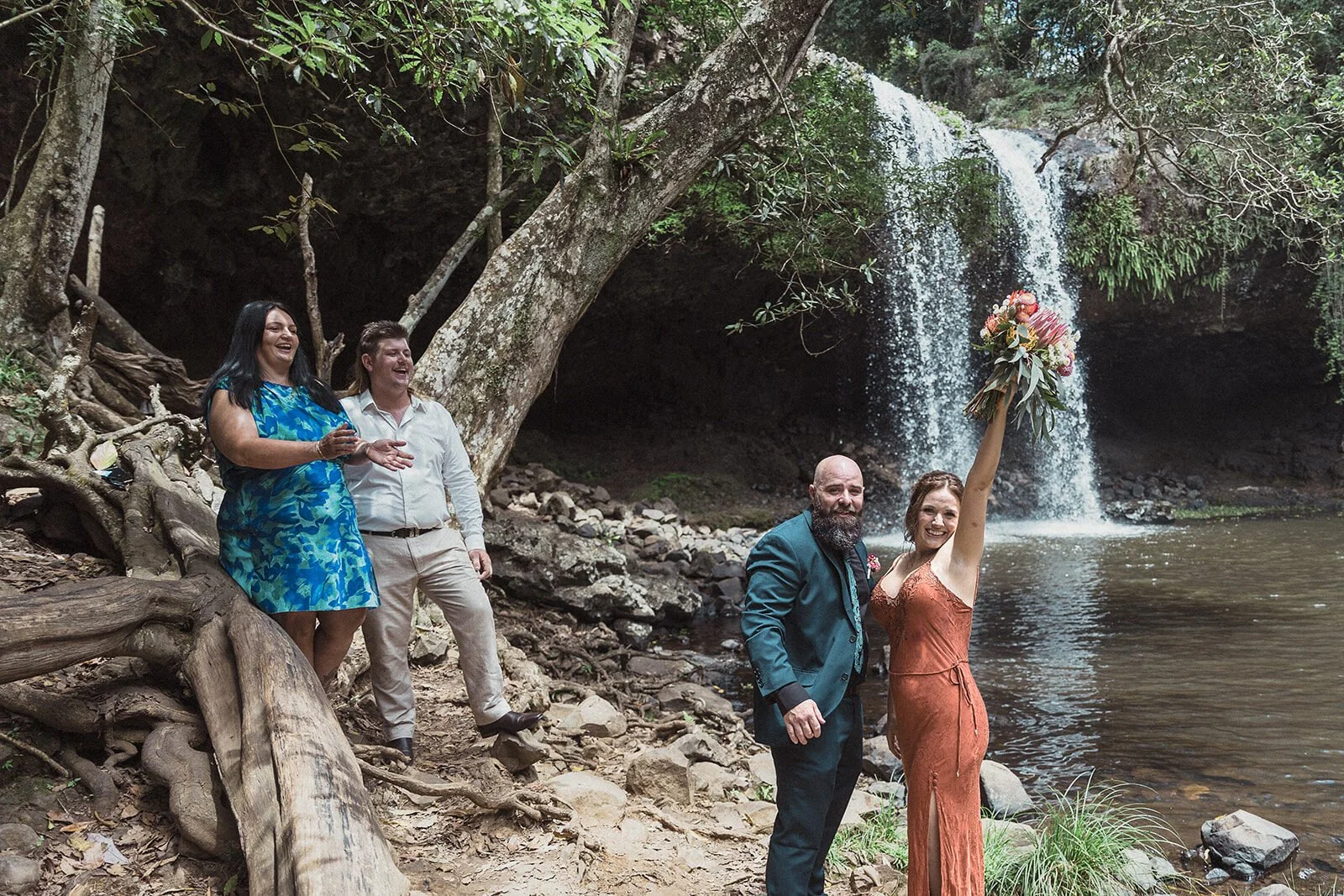 Bride raising her bouquet to cheers from guests, Sara and Graeme's elopement at Killen Falls, Northern Rivers