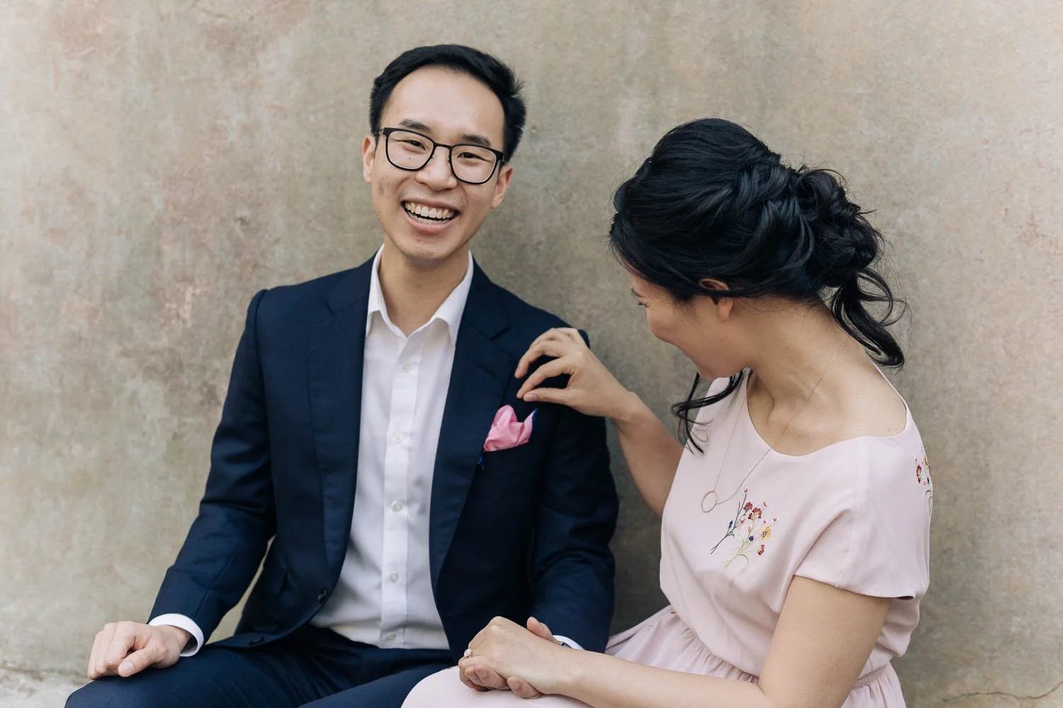 Couple laughing together on a sandstone ledge during their pre-wedding shoot in The Rocks