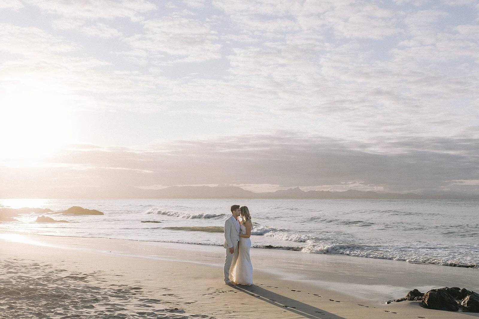 Couple embracing on the shore at sunset, Abby and James' elopement at Little Wategos Beach, Byron Bay