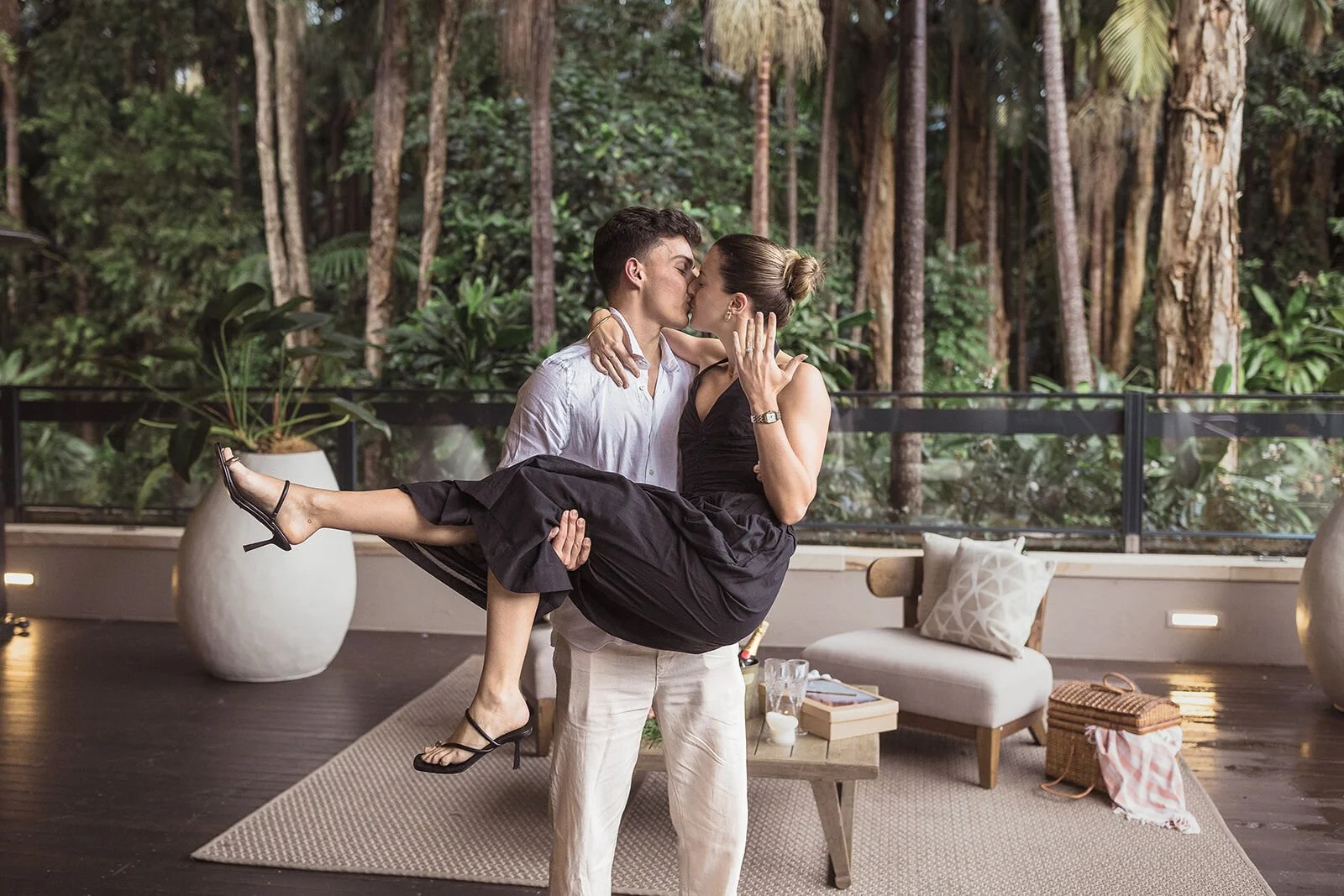 Man carrying his fiancée and kissing her on the deck, Ben and Chloe's marriage proposal in Byron Bay