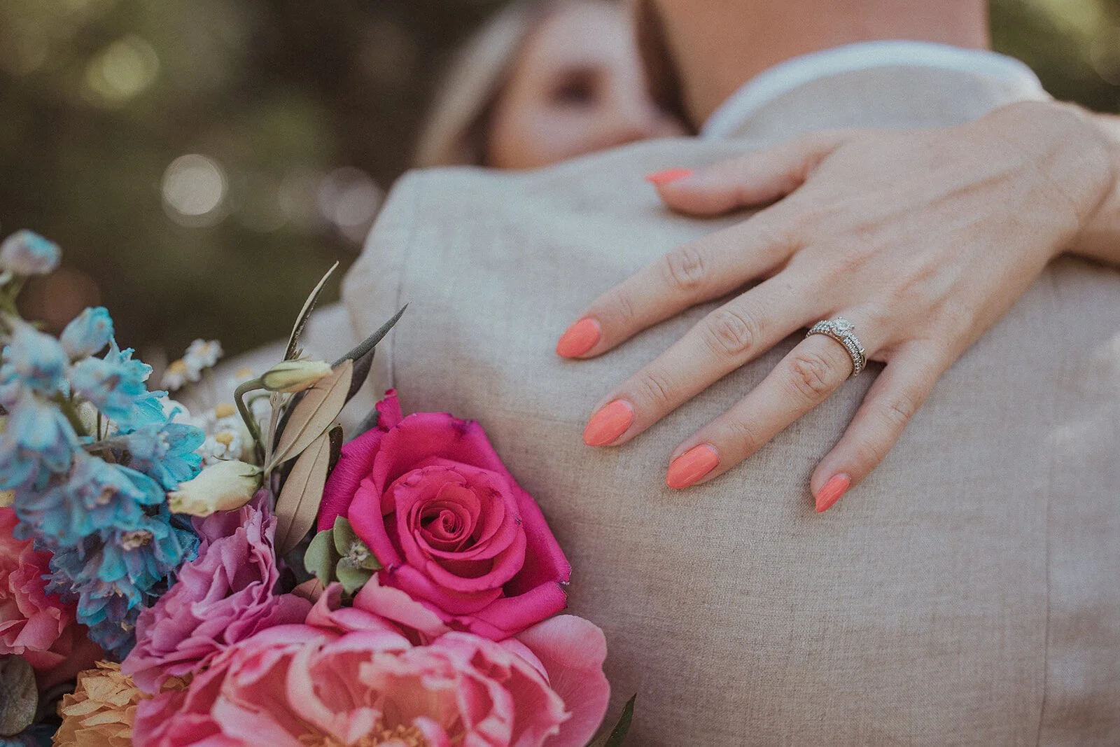 Detail of the bride's hand and ring over the groom's shoulder beside the bouquet, Eliza and Greg's elopement at Broken Head, Byron Bay