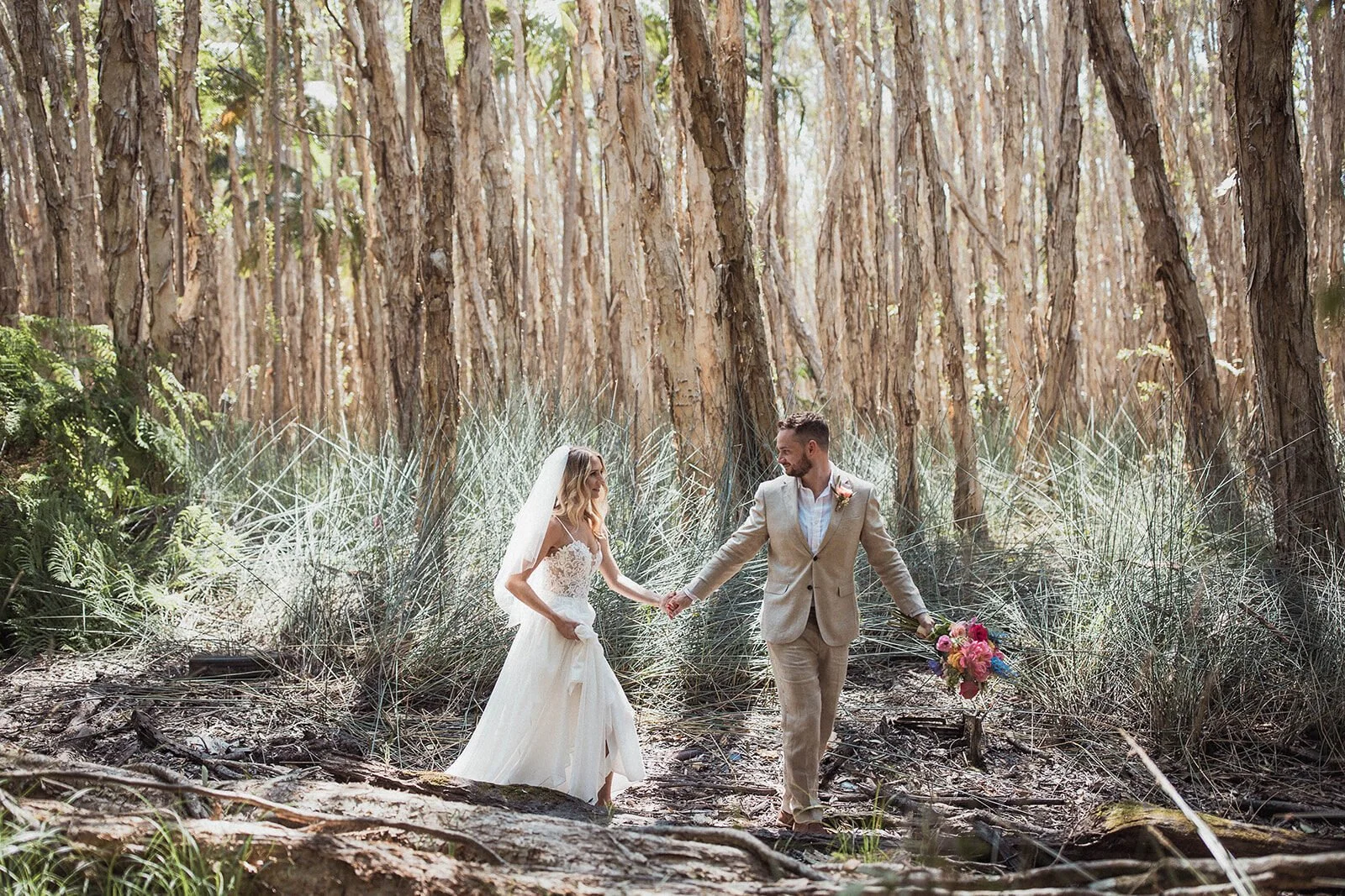 Couple walking hand in hand through the paperbark trees, Eliza and Greg's elopement at Broken Head, Byron Bay