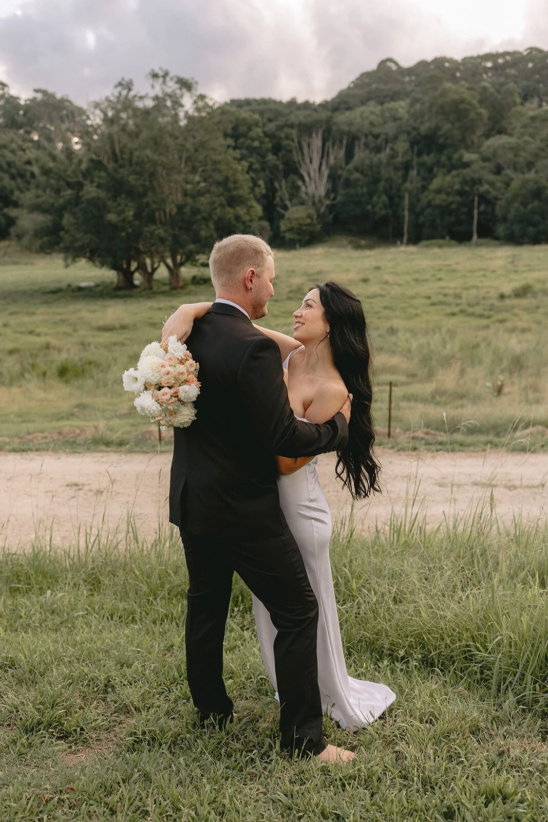 Couple embracing beside a dirt track, Kobi and Darren's elopement at Butterfly Lane, Byron Bay hinterland
