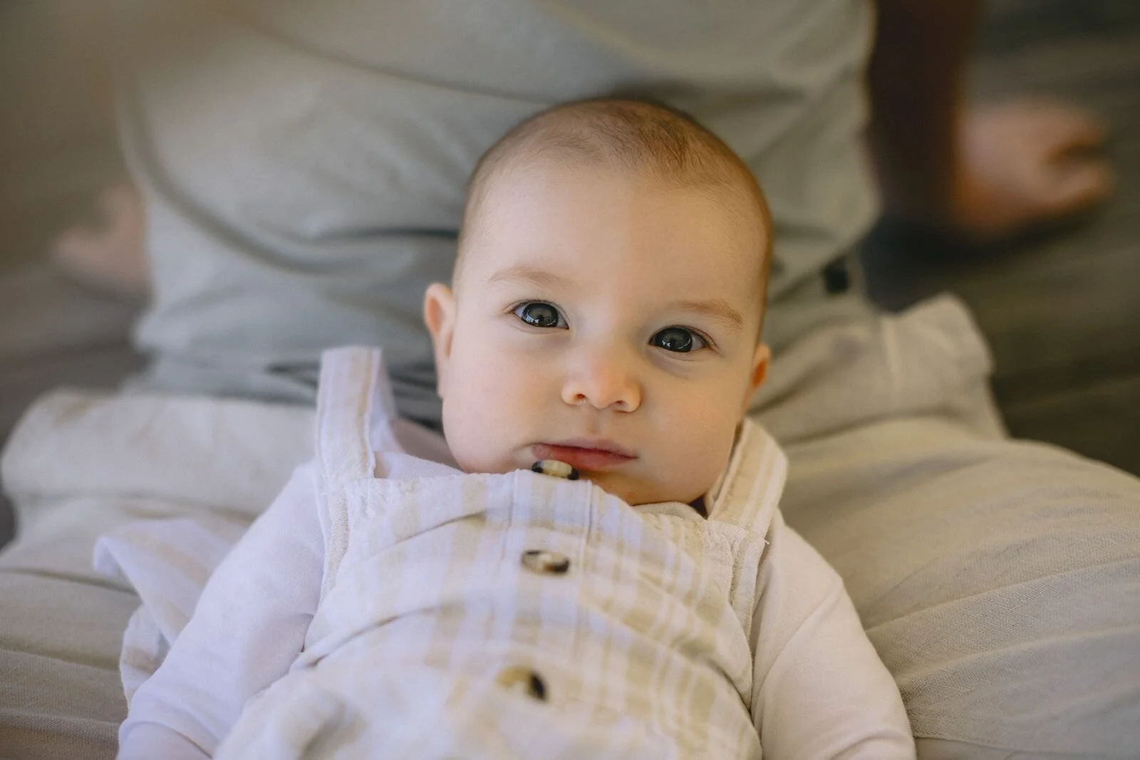 Close-up of a baby girl lying in her dad's lap looking up with big eyes