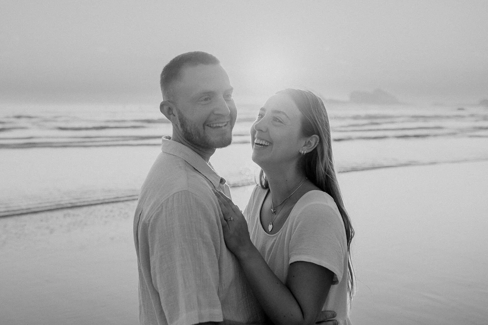 Black and white of the couple laughing together, Charlie and Hannah's sunrise marriage proposal at Broken Head Beach, Byron Bay