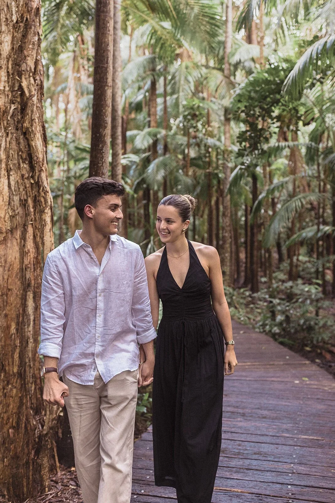 Couple laughing and walking together on the boardwalk, Ben and Chloe's marriage proposal in Byron Bay