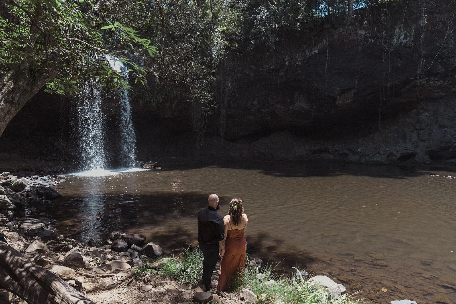 Couple standing by the water looking at the waterfall, Sara and Graeme's elopement at Killen Falls, Northern Rivers