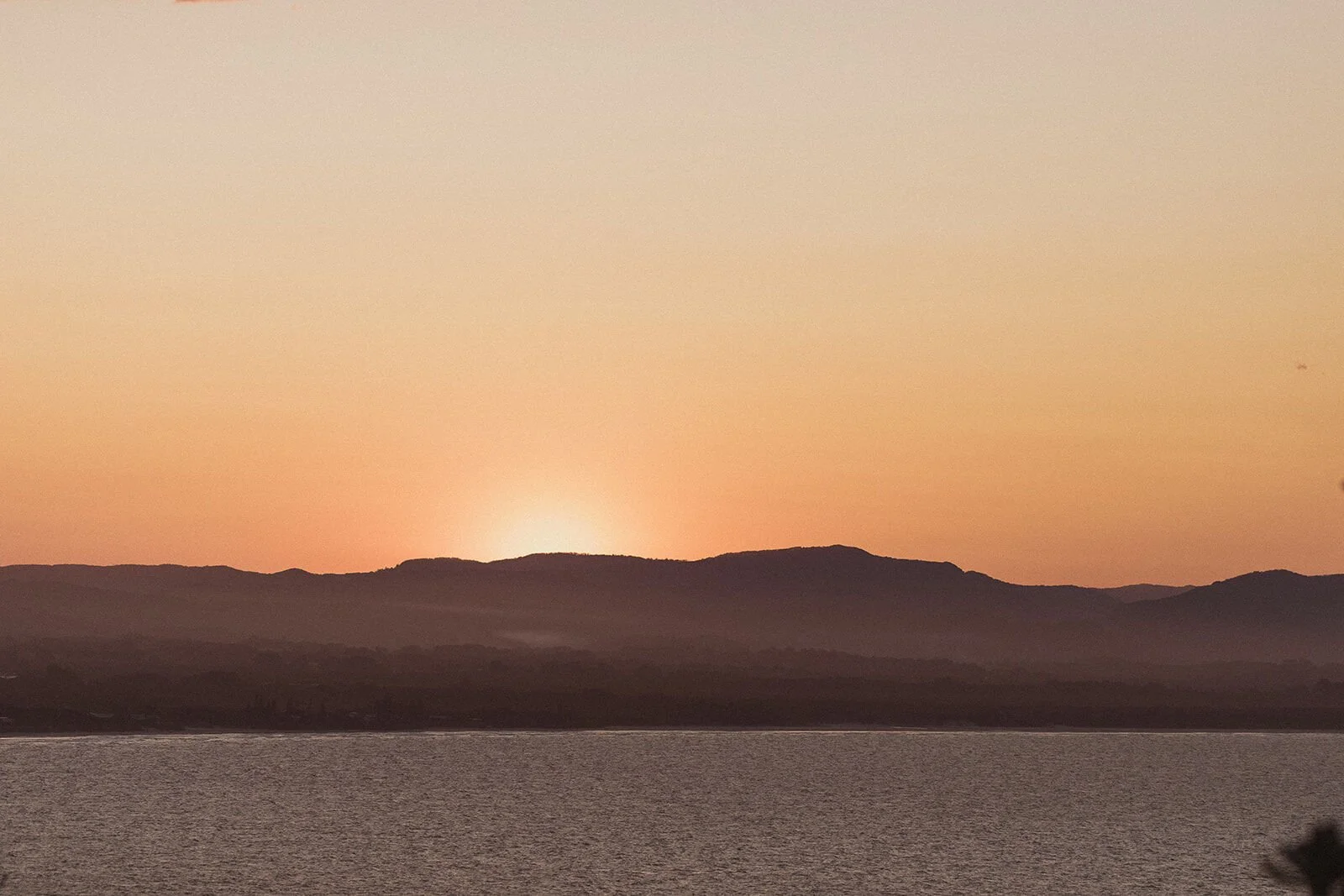Sun setting behind the hills across the bay, Douglas and Ying's sunset marriage proposal at Cape Byron Lighthouse, Byron Bay