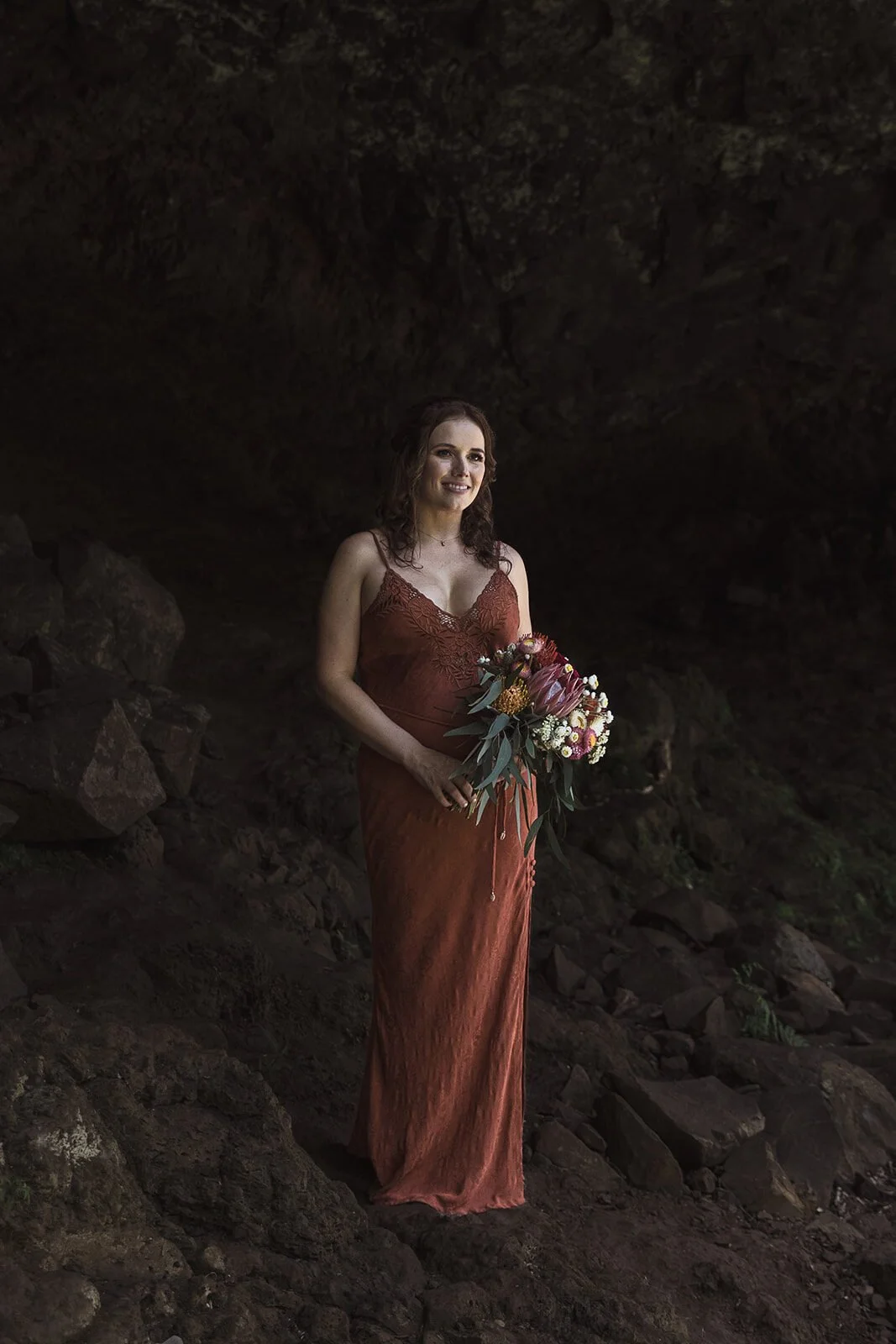 Bride in a rust dress holding her bouquet, Sara and Graeme's elopement at Killen Falls, Northern Rivers