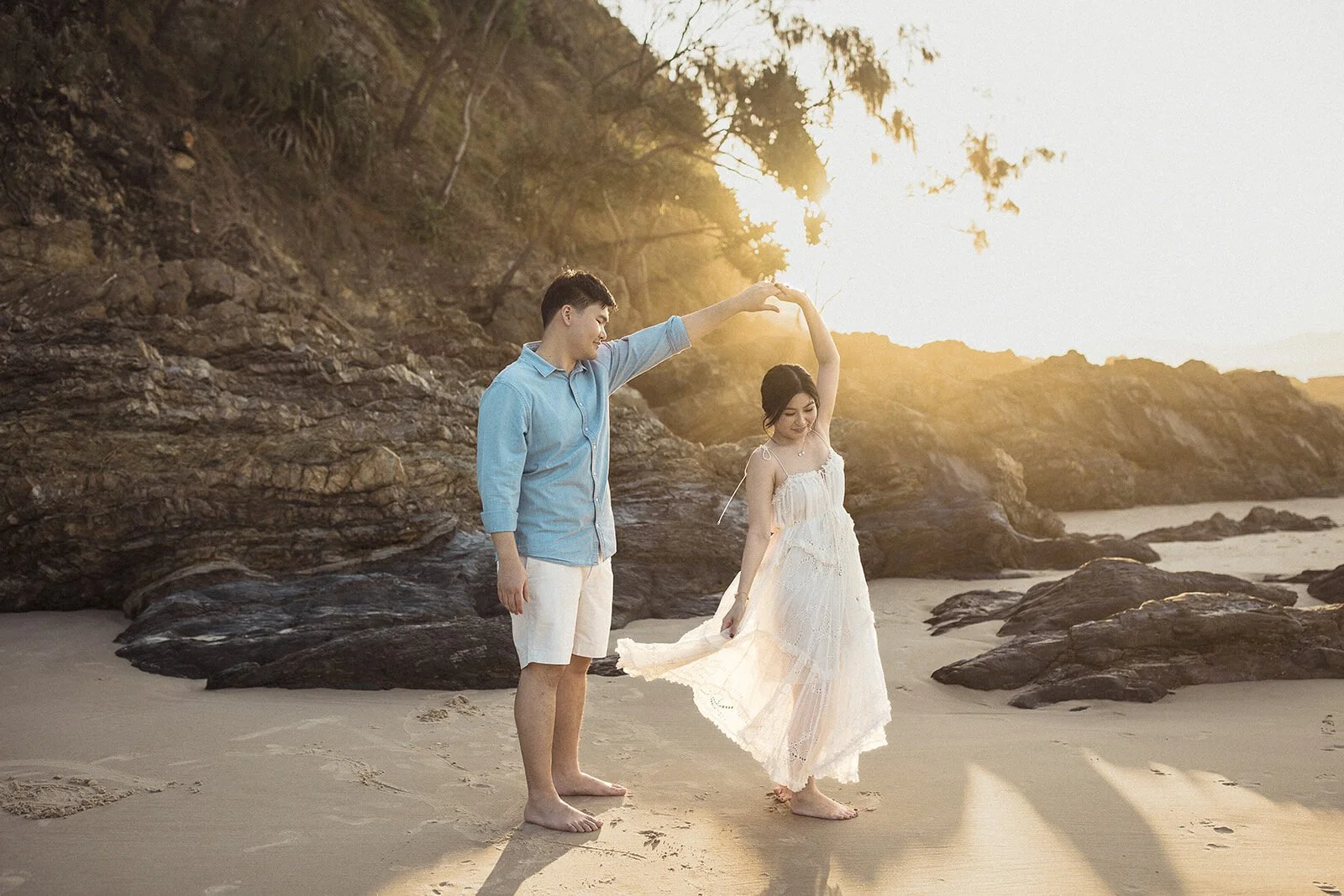Groom twirling the bride on the beach at sunset, Maggie and William's pre-wedding photos in Byron Bay