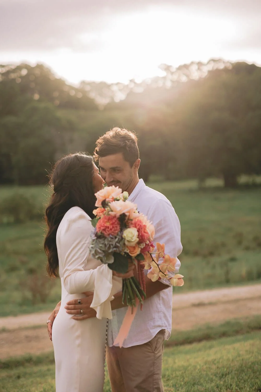 Groom kissing the bride’s forehead at golden hour in the Byron hinterland