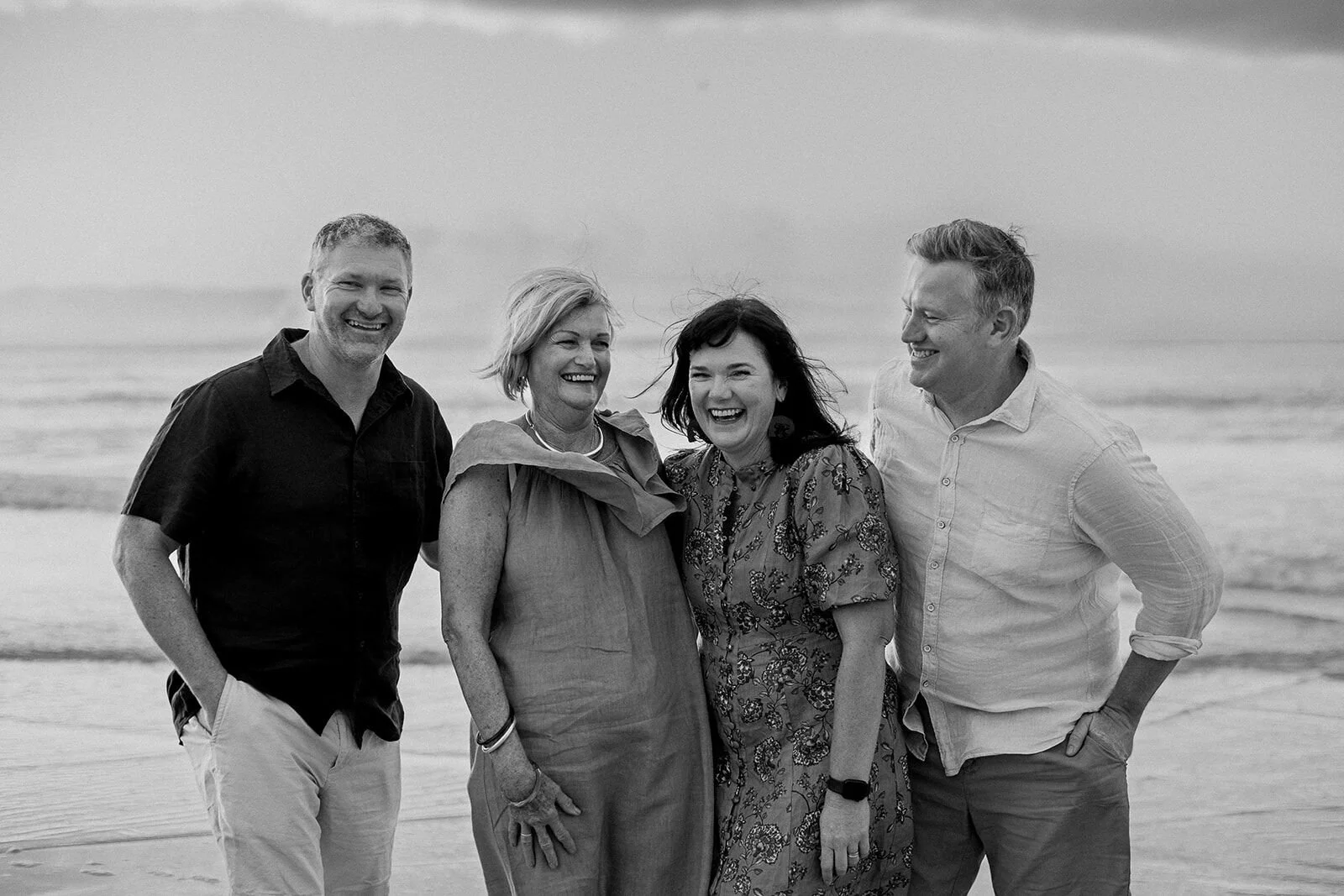 Black and white portrait of two couples laughing together on the beach