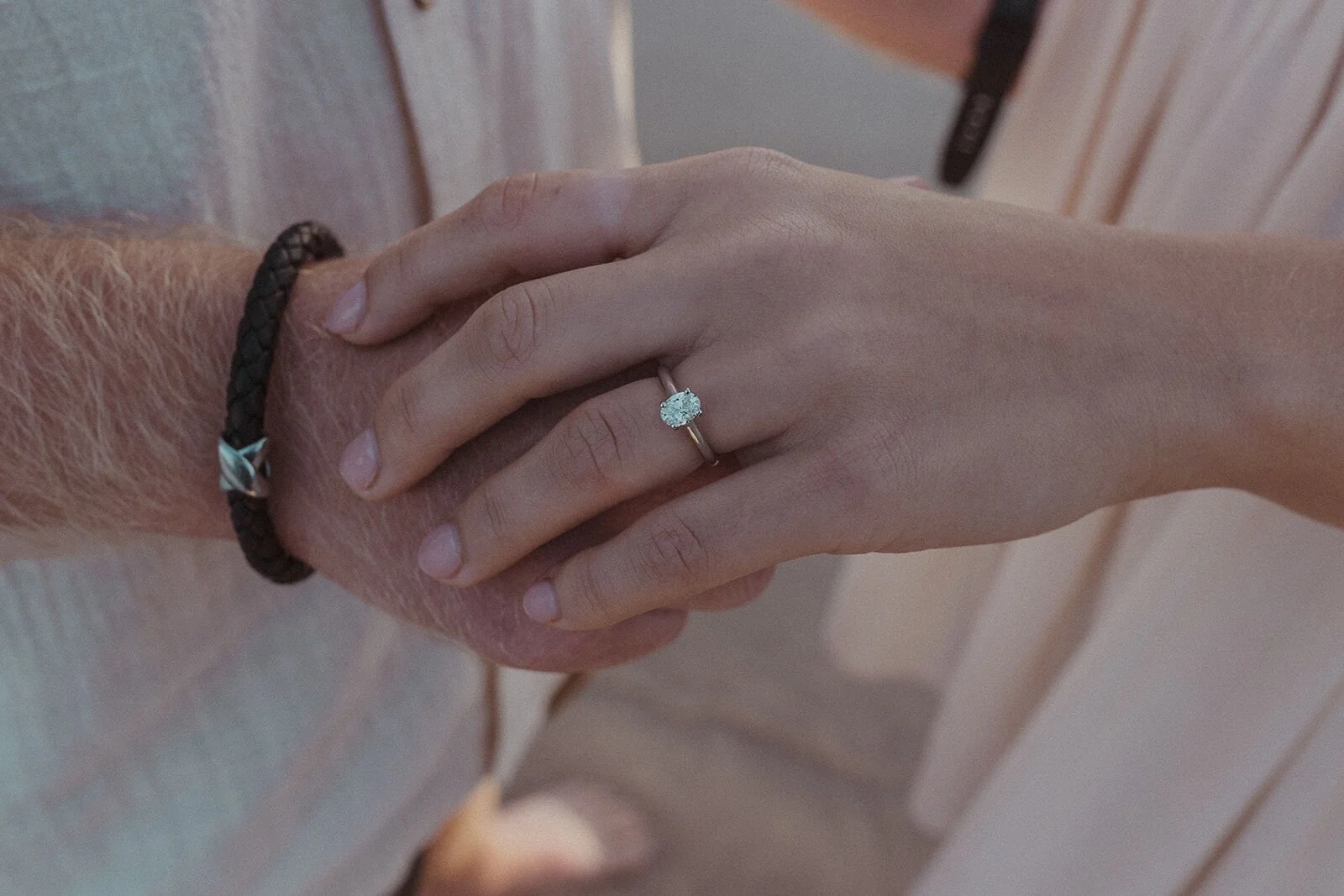 Close up of the engagement ring on her hand over his wrist, Charlie and Hannah's sunrise marriage proposal at Broken Head Beach, Byron Bay
