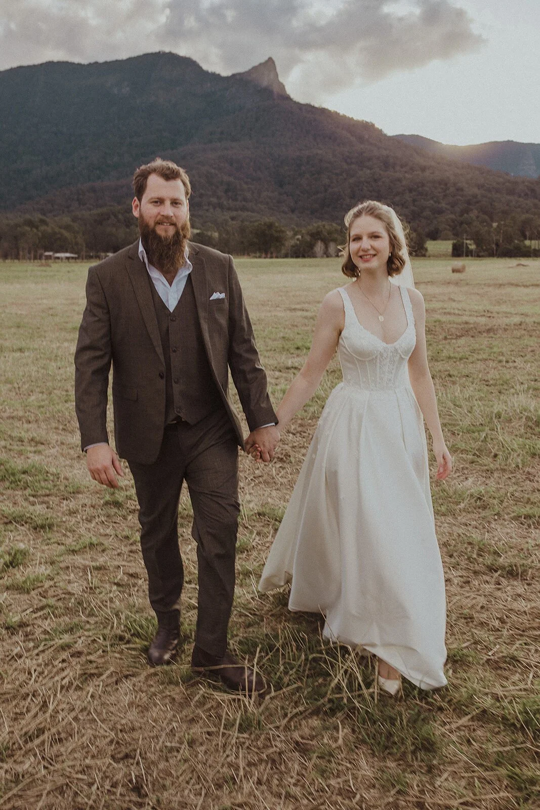Couple holding hands and walking in the hay paddock, Sam and Tom's elopement at Highfield Farm, Northern Rivers