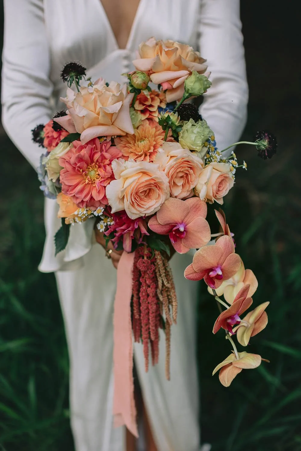 Bride holding a bouquet of peach roses, dahlias and orchids