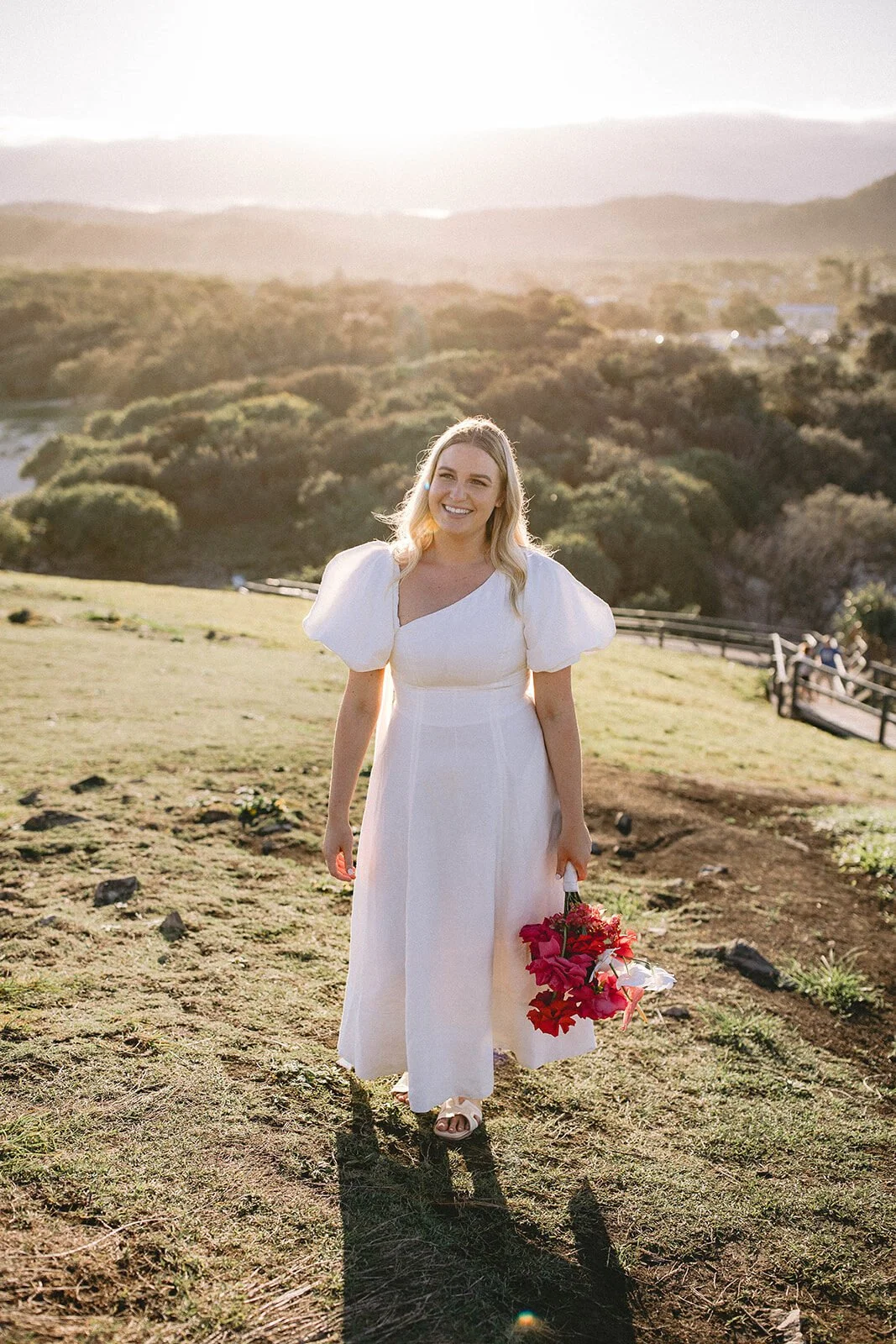 Bride smiling and walking toward the camera in golden light, Brittany and Mark's elopement at Cabarita Beach, Northern Rivers