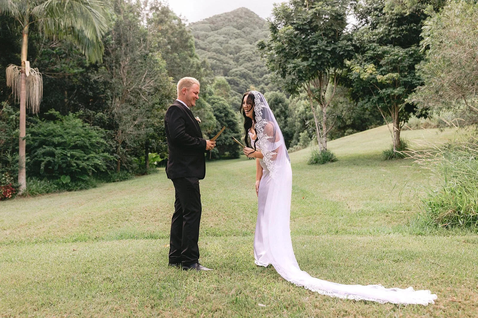 Bride in a long veil and groom standing on the lawn, Kobi and Darren's elopement at Butterfly Lane, Byron Bay hinterland