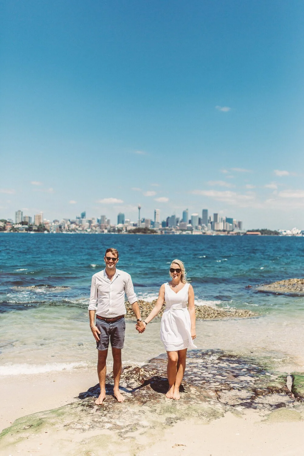 Eloping couple on the rocks of Shark Island with the Sydney city skyline behind