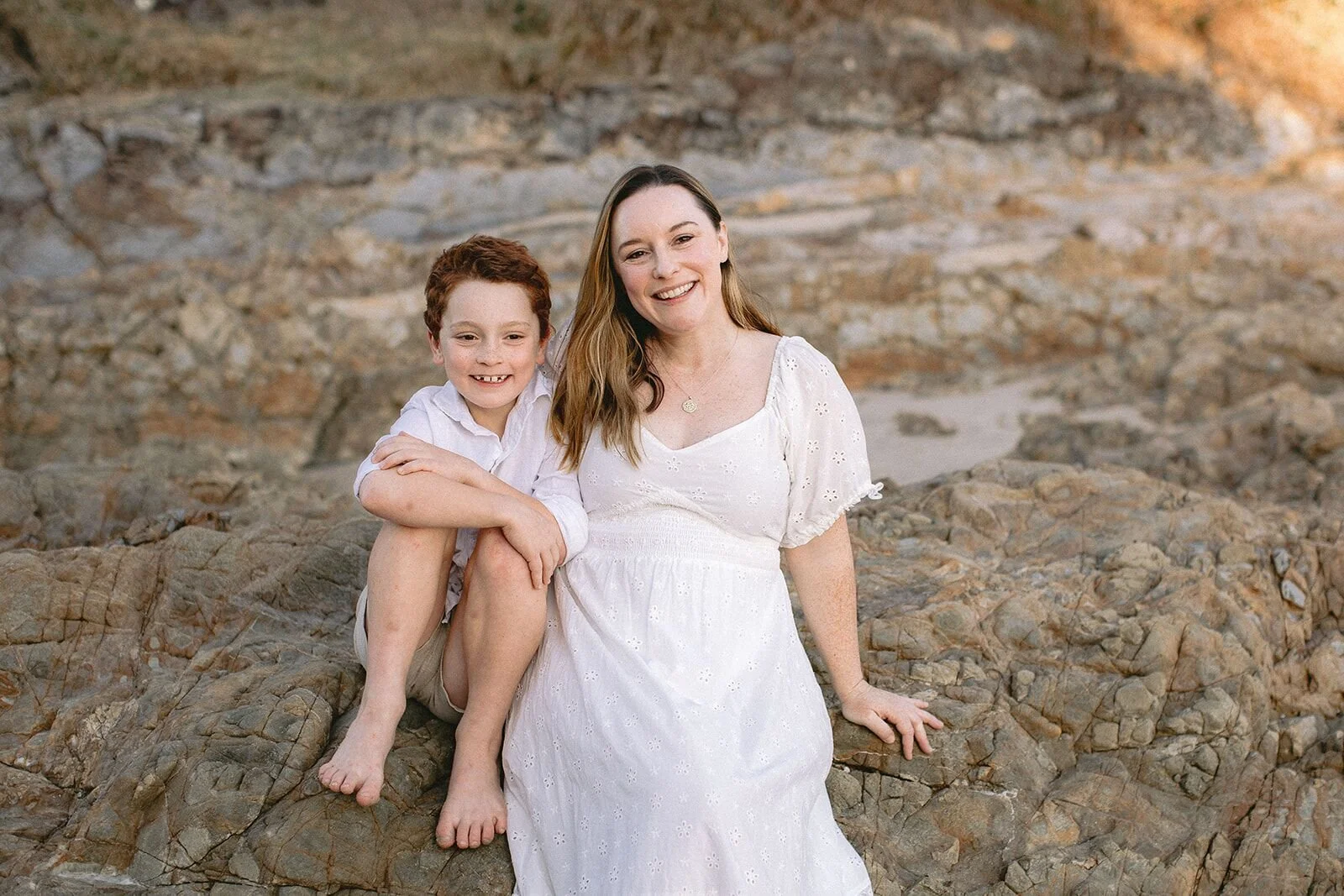 Mum and her young son sitting side by side on the golden rocks